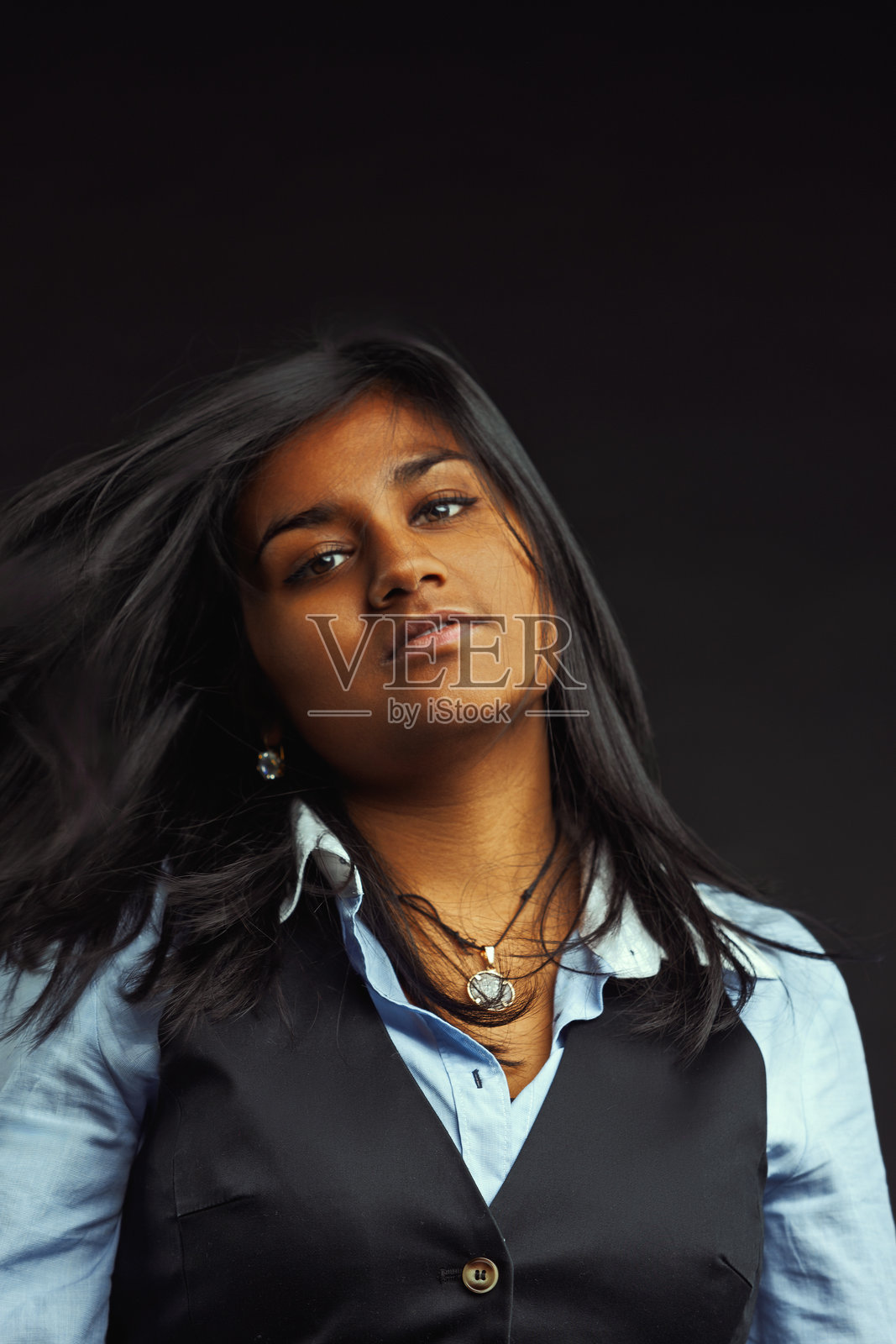 年轻的印度女性在摄影棚中摆姿势，头发随风飘动照片摄影图片