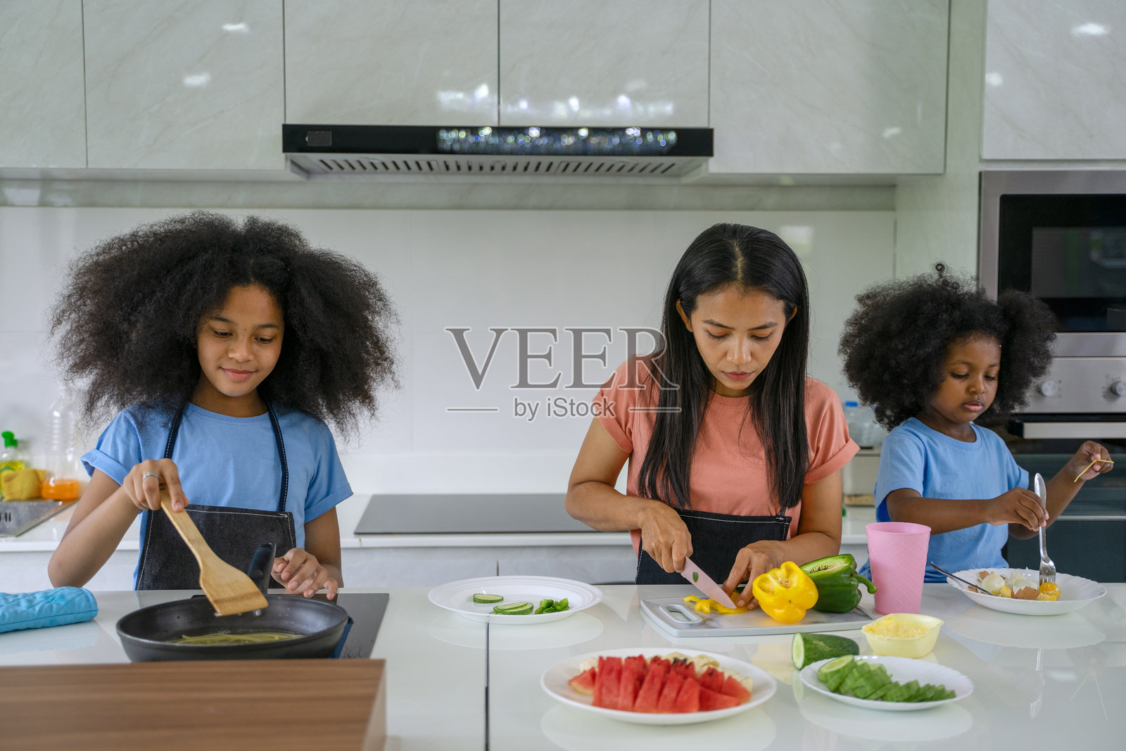 母亲和女儿们在厨房里做饭。照片摄影图片