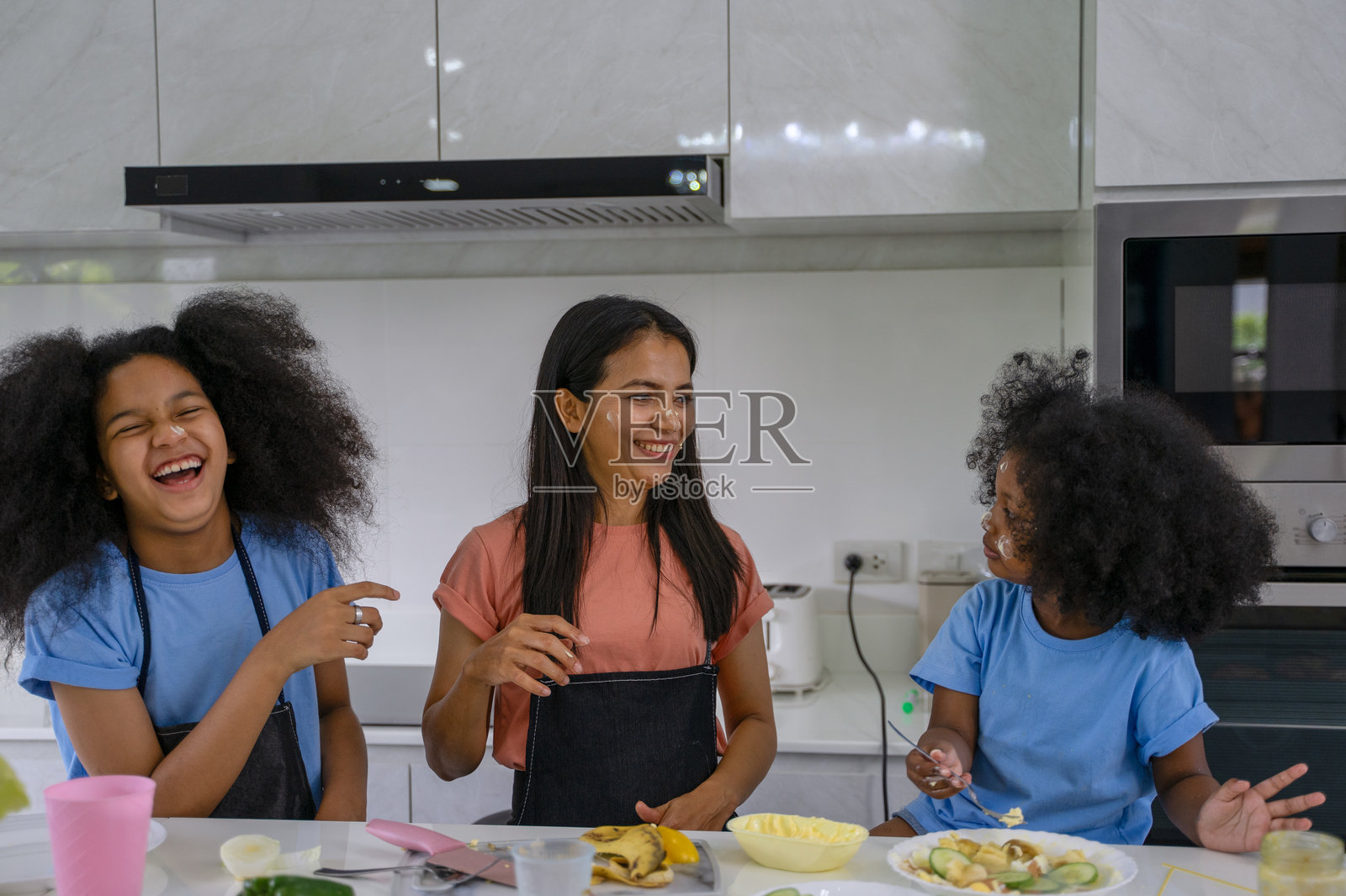 母亲和女儿们在厨房里做饭。照片摄影图片