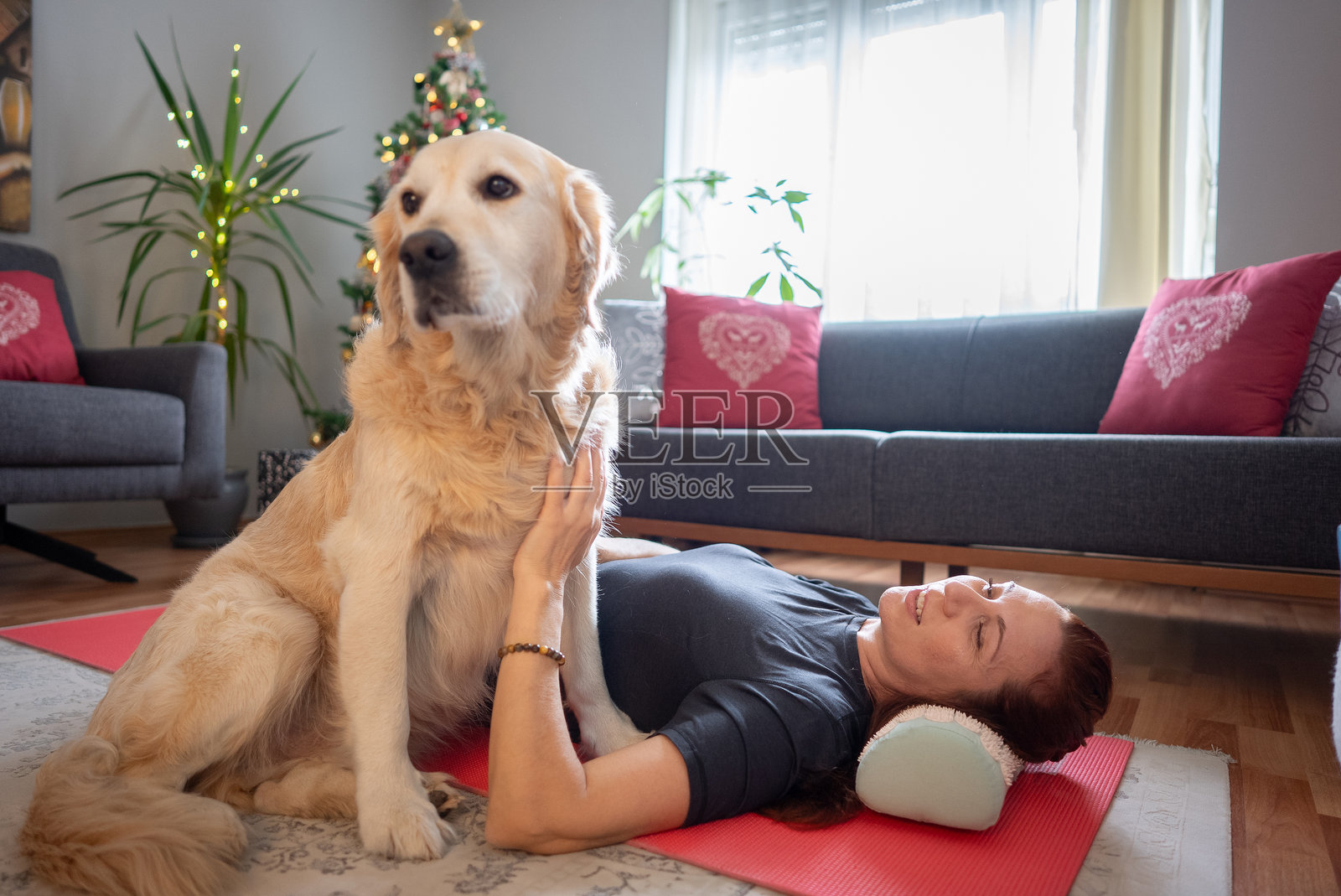 圣诞早晨，女人在客厅的垫子上锻炼，身边有她可爱的狗狗。照片摄影图片