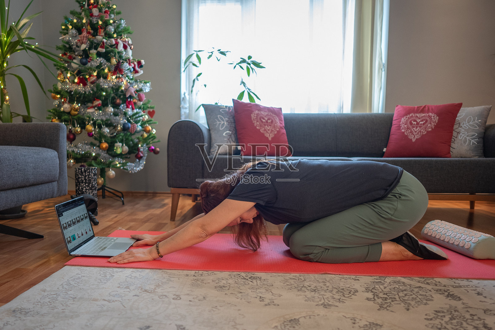 圣诞早晨，一位成熟的运动女性在笔记本电脑前锻炼。照片摄影图片