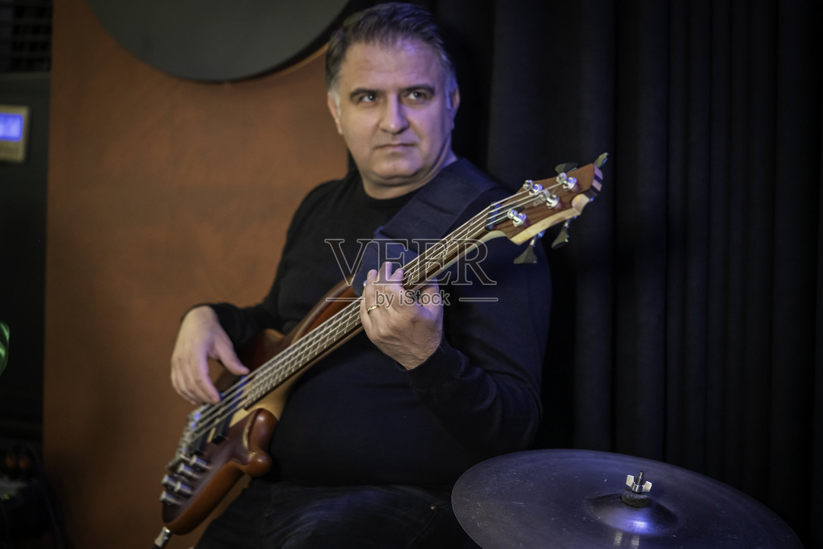 男性贝斯手在舞台上水平练习。照片摄影图片