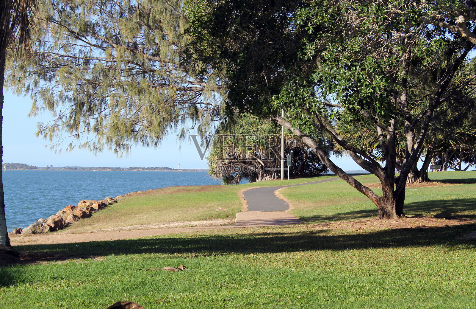 昆士兰州格拉德斯通的斯皮纳克公园旁边，海洋边缘的小径穿过草地和树木。照片摄影图片