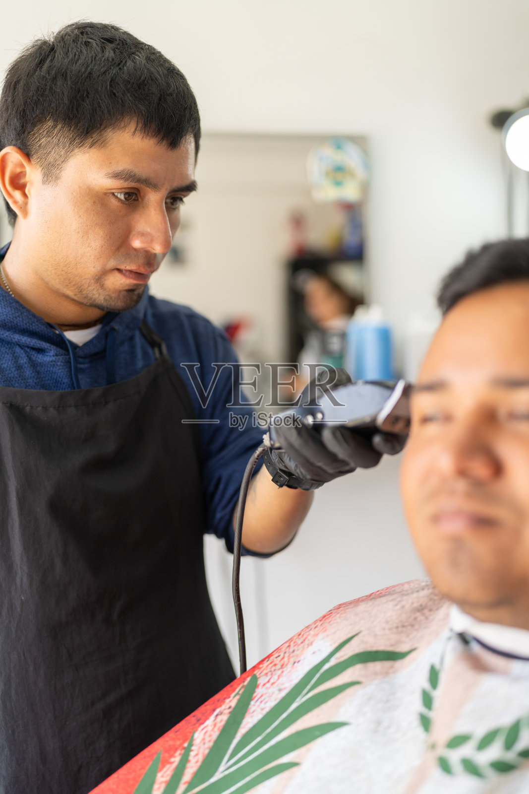 理发师使用电动剃须刀为顾客剪发照片摄影图片