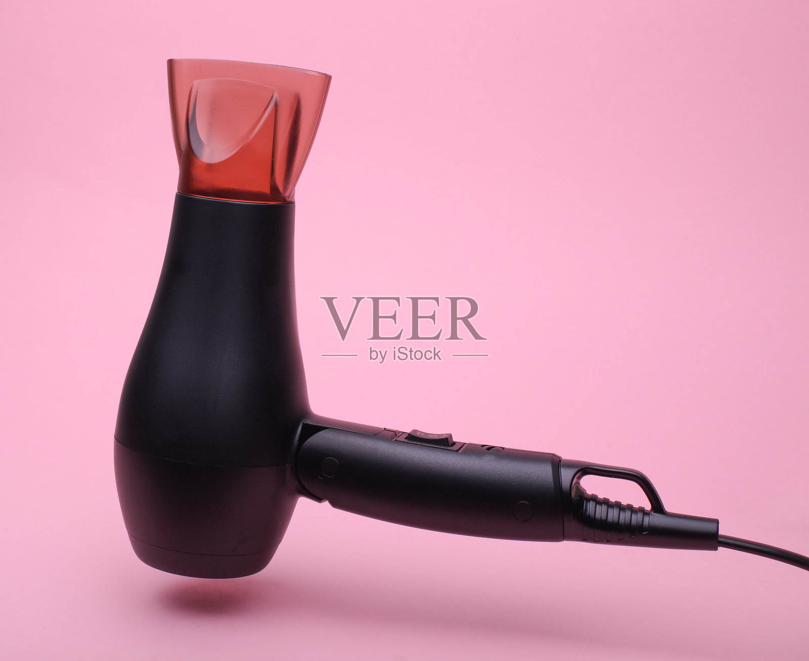 黑色吹风机漂浮在粉色背景上照片摄影图片