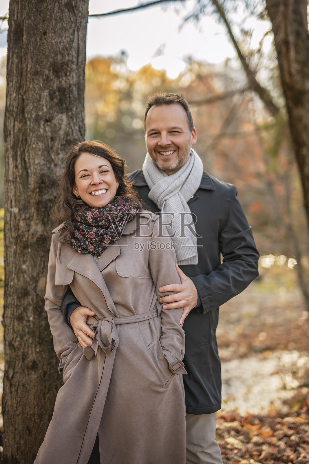 在公园长椅上相拥的情侣。可爱的情侣在秋天的户外亲吻。照片摄影图片