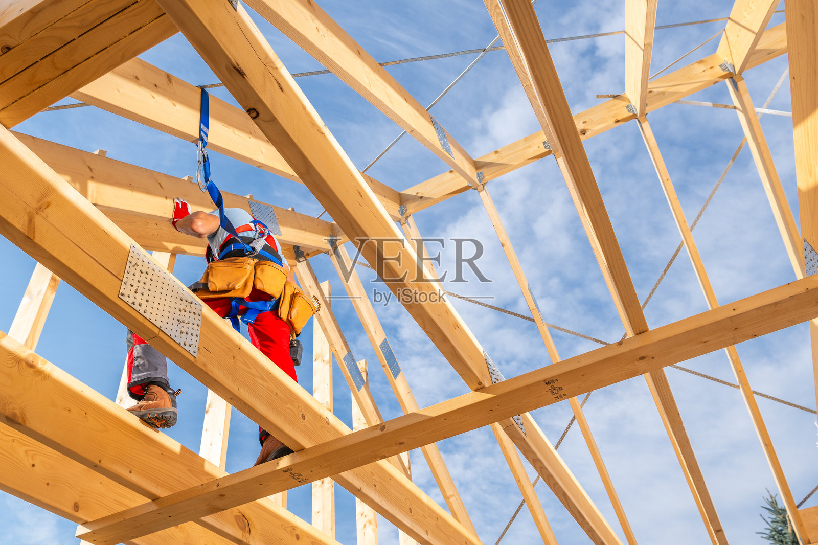 建筑工人在晴朗的蓝天下为建筑工地固定屋梁照片摄影图片