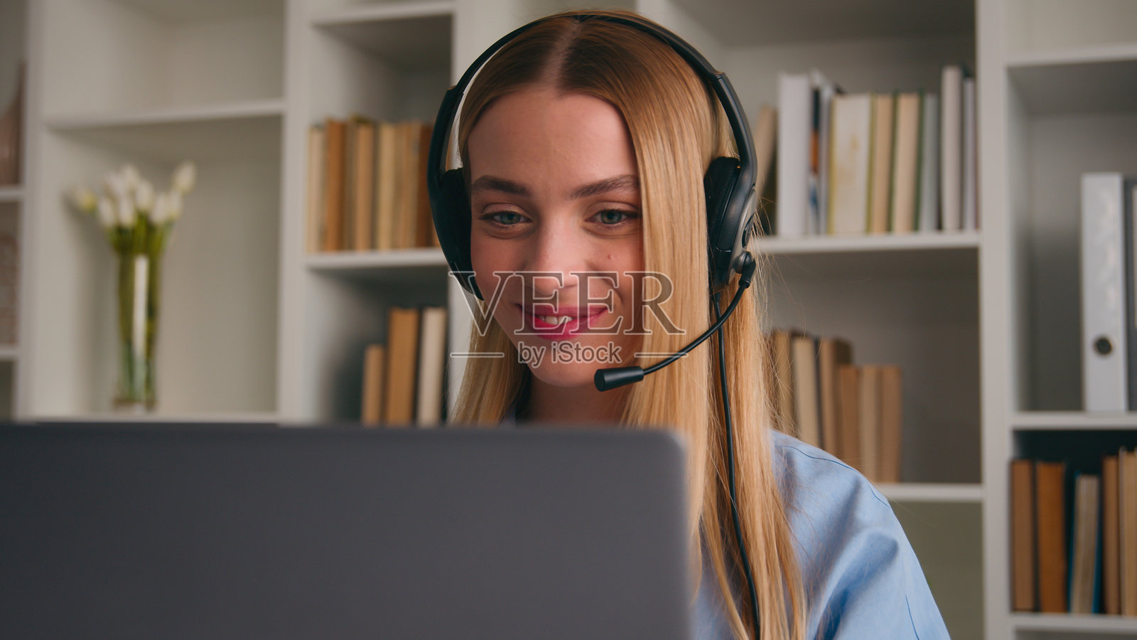 白人女性商务女孩远程学生互联网教师视频通话会议课堂课程在线学习虚拟会议点头表示同意，佩戴耳机听音乐，使用笔记本电脑在办公室工作照片摄影图片