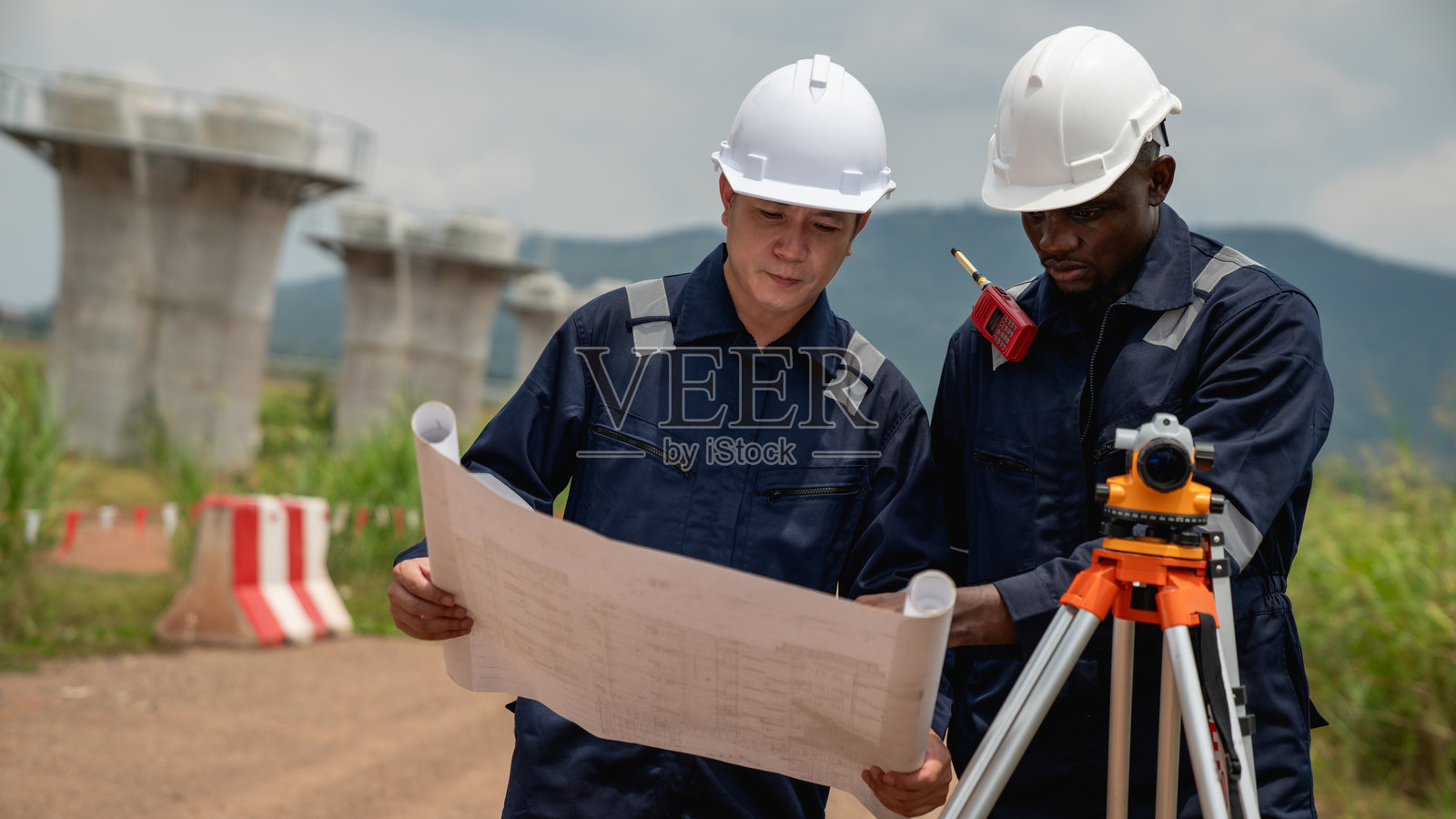 测量团队正在使用经纬仪和道路施工图纸进行测量。土木工程师正在使用测量工具收集施工项目的数据。照片摄影图片