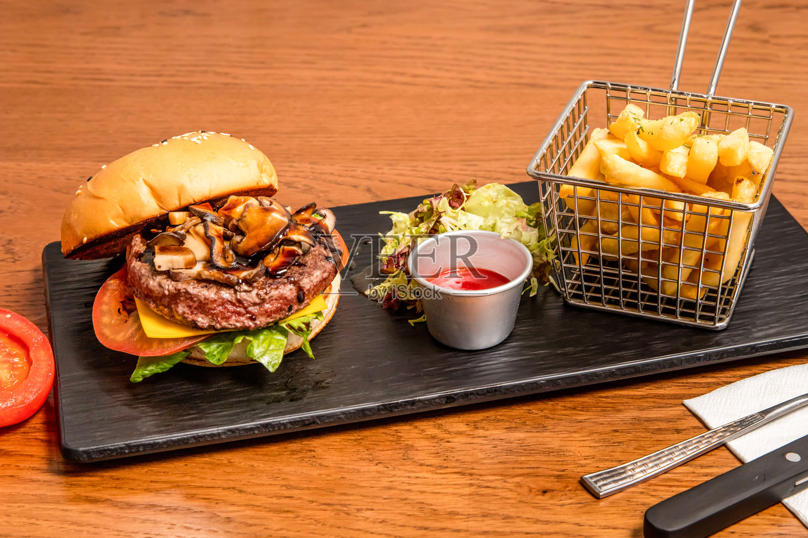 意大利醋烤蘑菇牛肉奶酪汉堡，配有番茄酱和薯条，摆放在木桌上的侧面视图，展现意大利快餐。照片摄影图片
