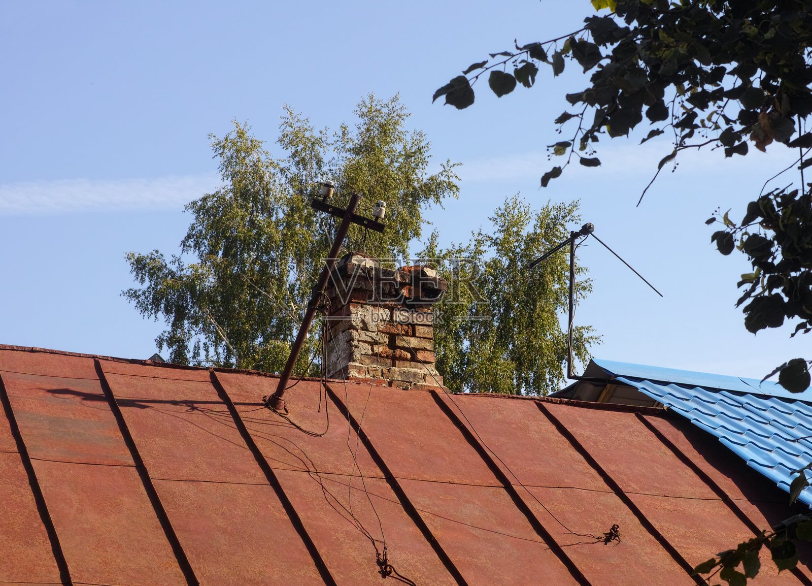 老砖烟囱位于房屋的金属屋顶上。照片摄影图片