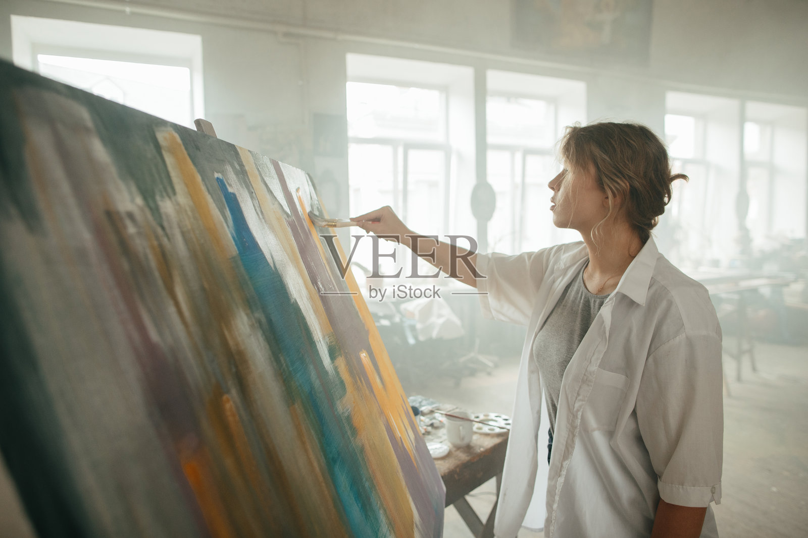 女性画家在创意空间中侧身作画照片摄影图片