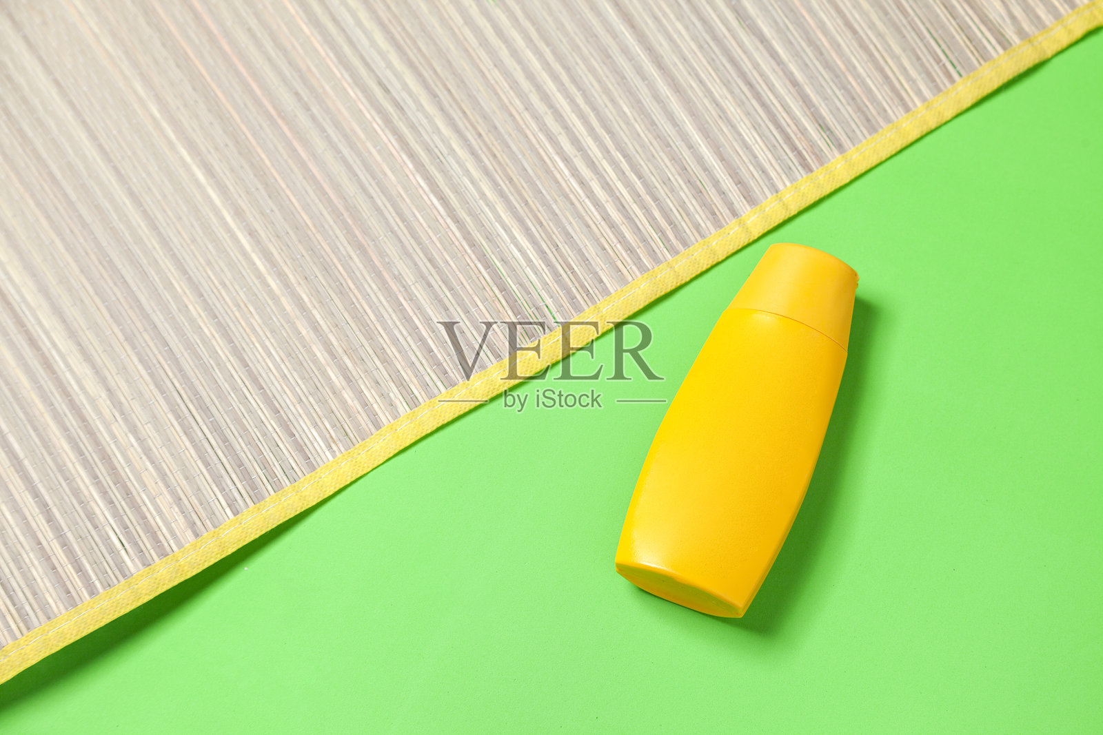 绿色背景上的防晒霜瓶和草垫。照片摄影图片