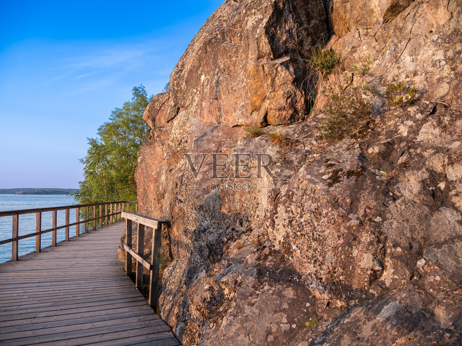 一条婴儿车道蜿蜒在海边，旁边是 jagged rocks。照片摄影图片