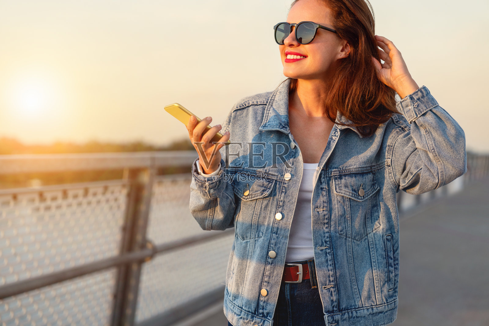 时尚的城市女性穿着休闲牛仔服装走在街道上。照片摄影图片