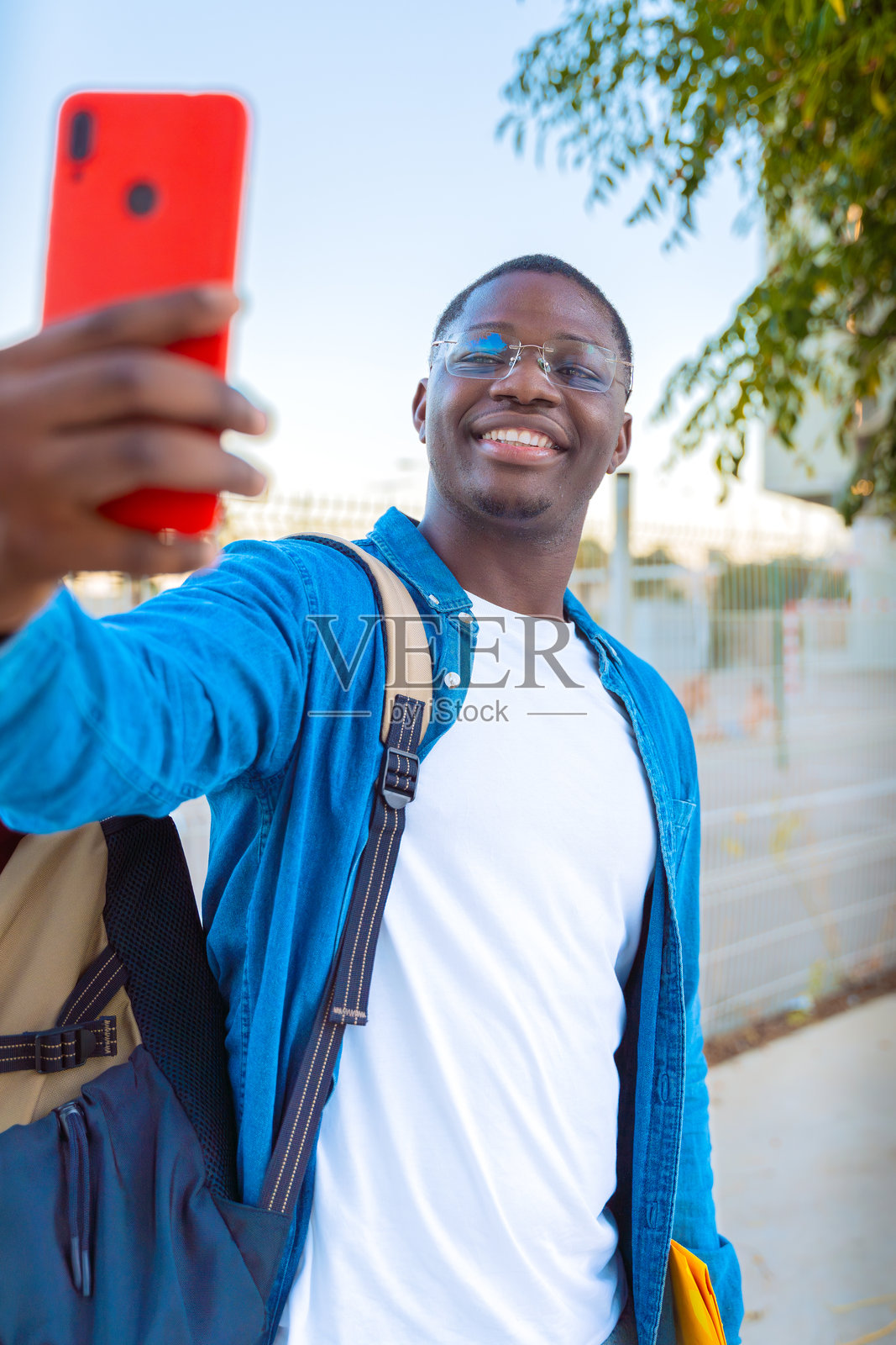 年轻男子在户外戴着眼镜，手持黄色文件夹自拍照片摄影图片