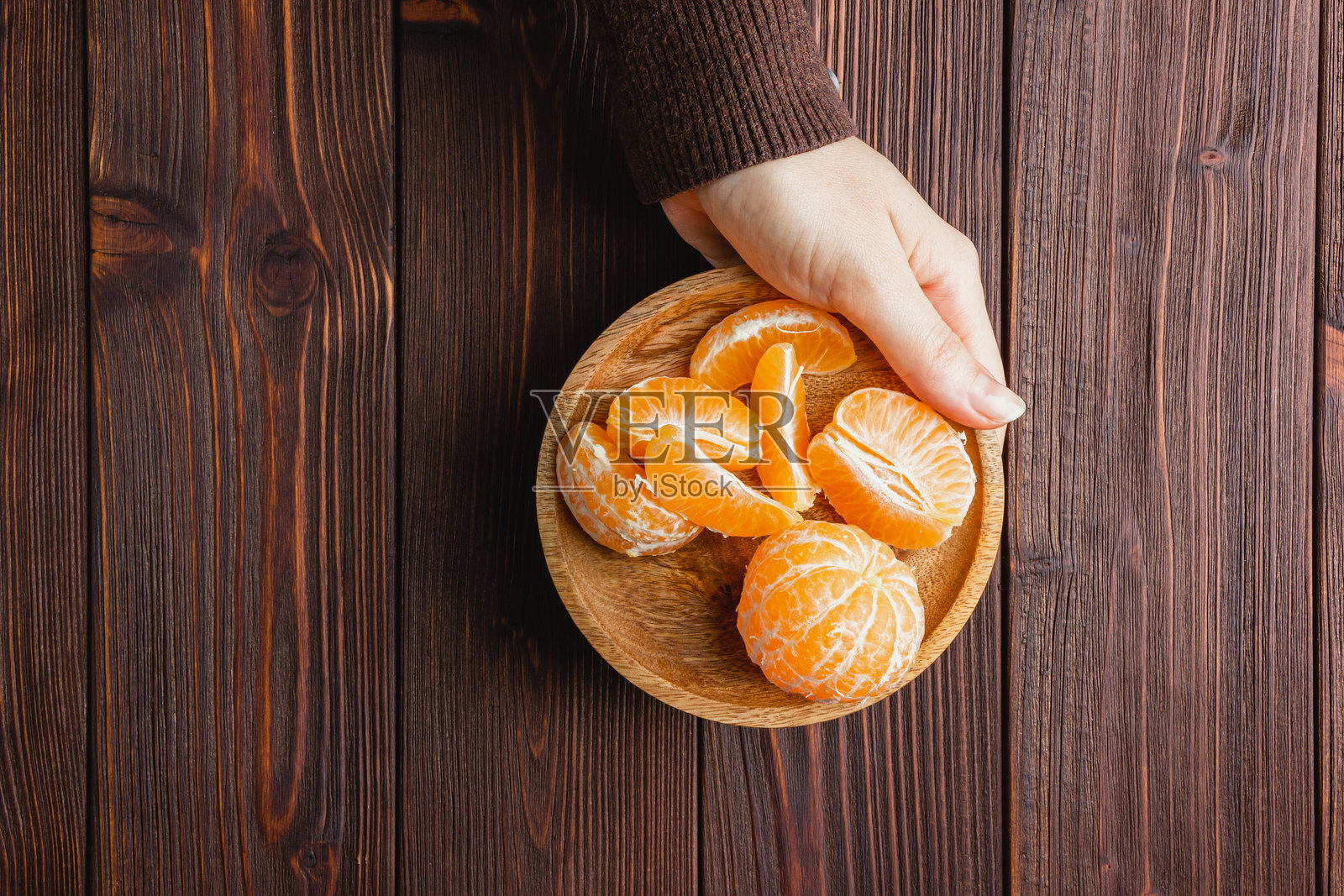 棕色木桌上的盘子里放着橘子。照片摄影图片