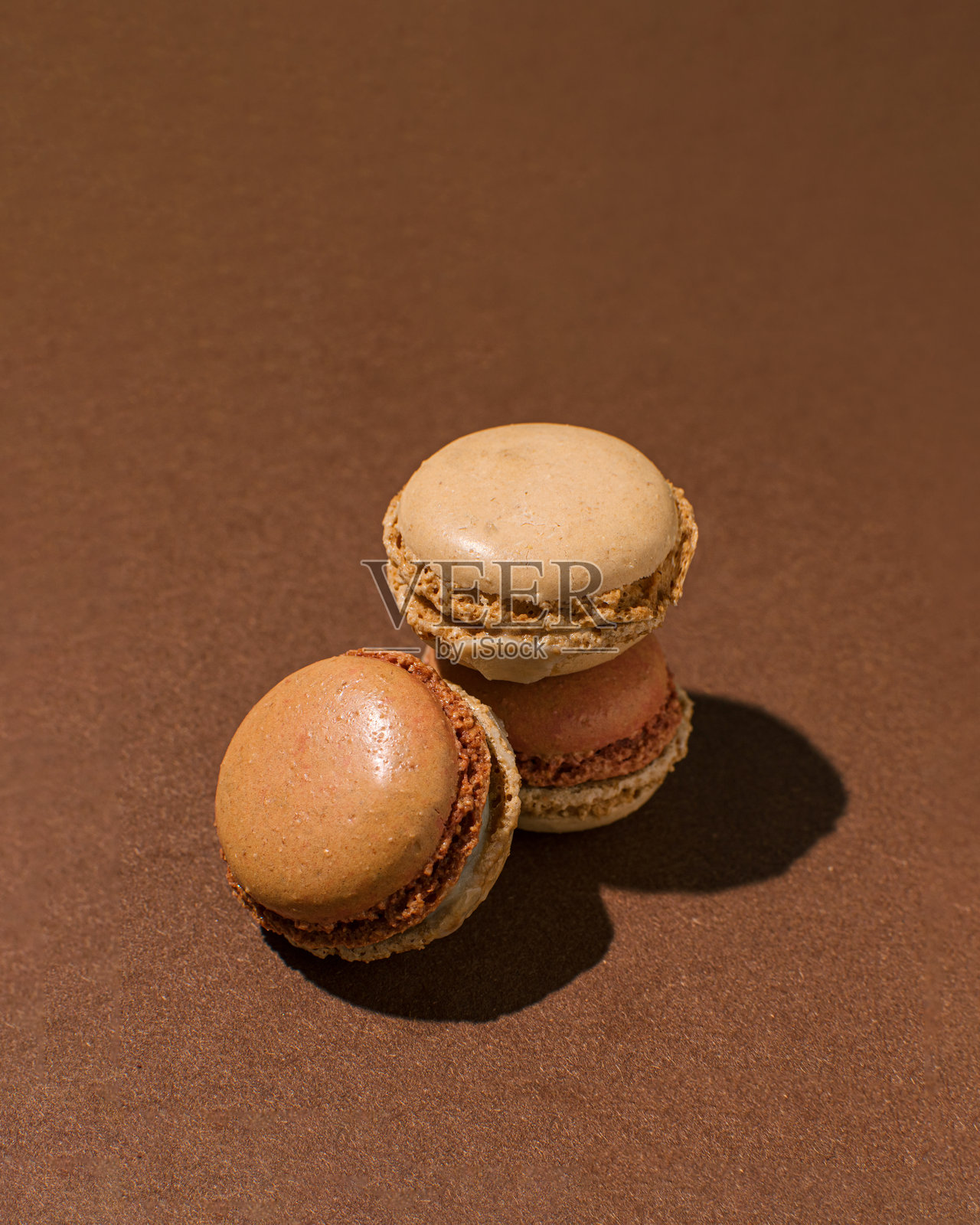 三块马卡龙放在巧克力棕色背景上