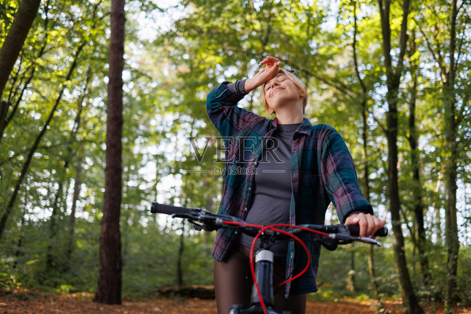 一位在森林中骑自行车的出汗女性停下来休息照片摄影图片