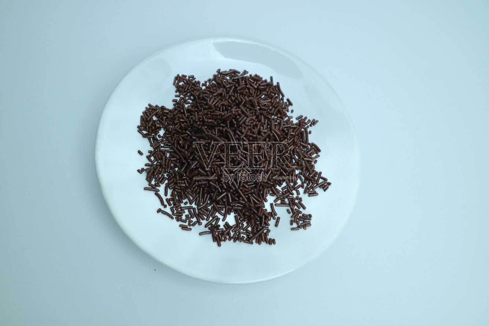 白盘上放着巧克力糖霜，背景为纯色。照片摄影图片