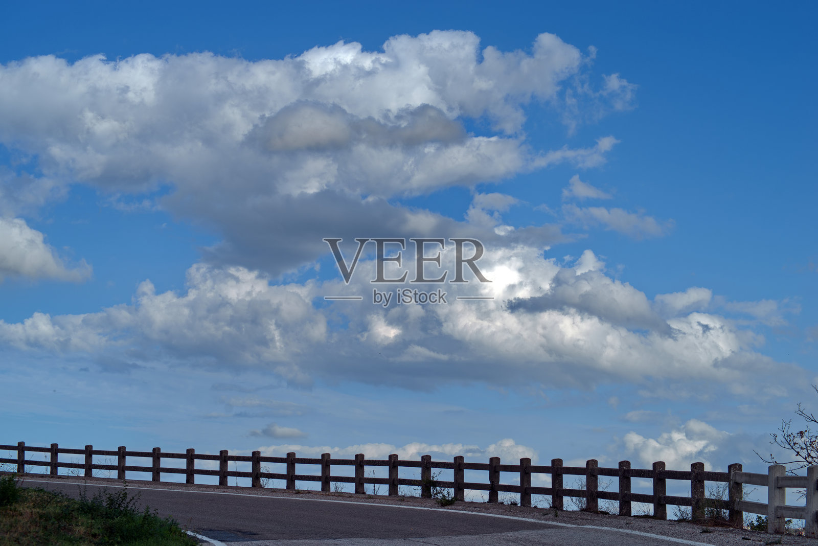 弯曲的道路与混凝土护栏在多云的天空下照片摄影图片