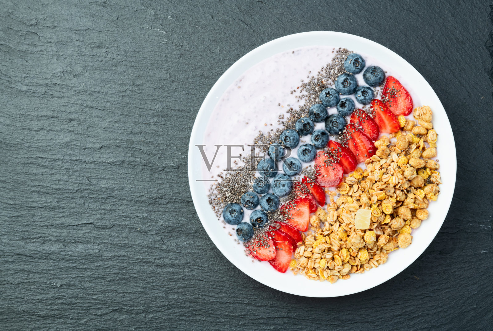 健康早餐。酸奶配浆果（草莓、覆盆子、蓝莓、黑莓）、燕麦片和奇亚籽。俯视图照片摄影图片