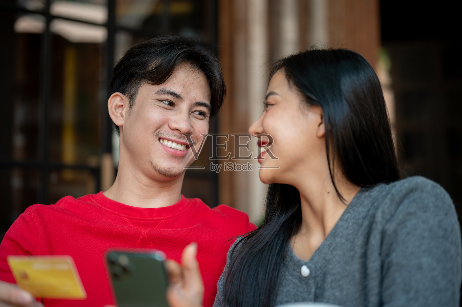 一对可爱的情侣在咖啡店里享受轻松的时光，一起在智能手机上网购。照片摄影图片