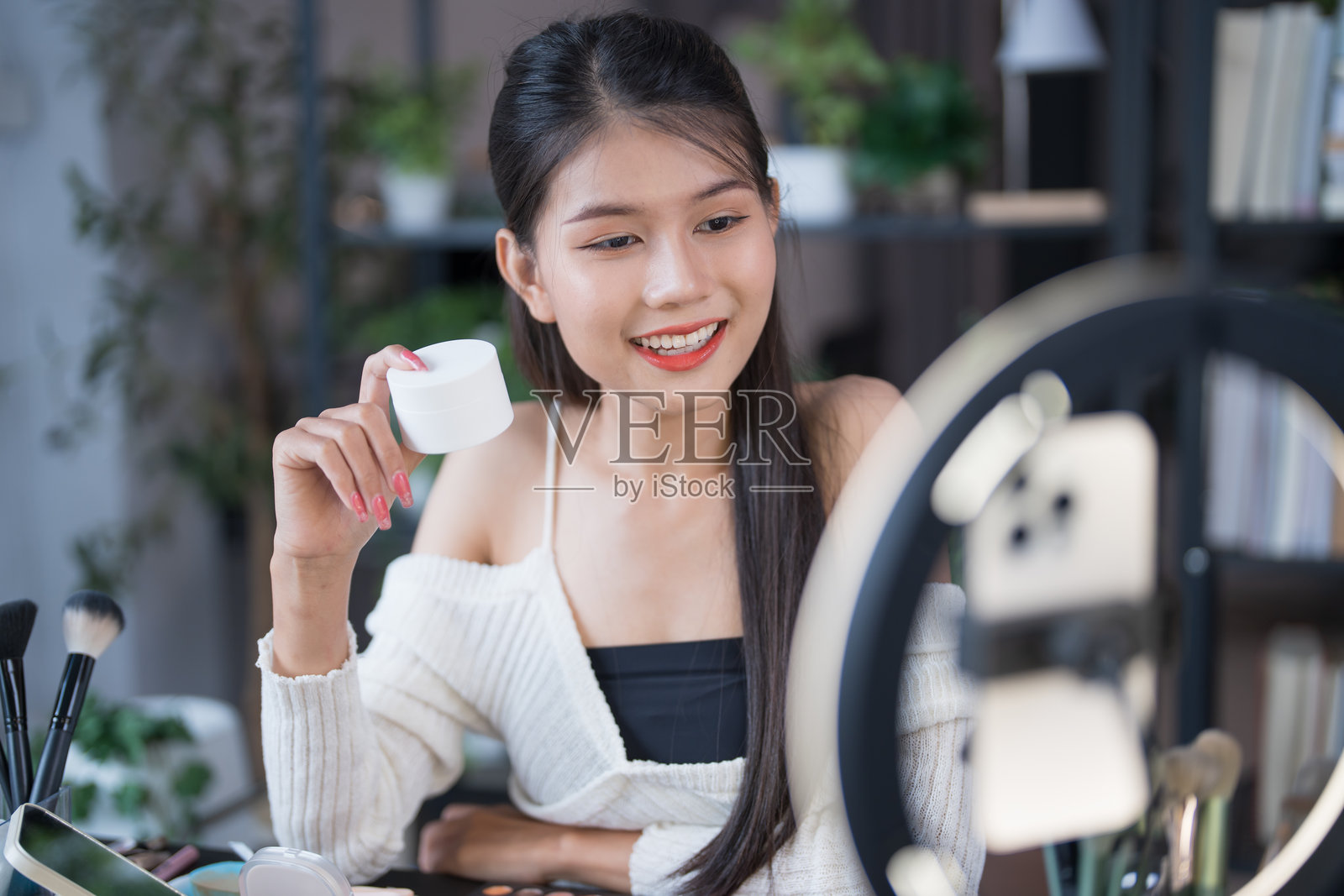 美容博主年轻亚洲女孩化妆师专业女性博主视频博主正在展示化妆品产品并录制视频，美容影响者亚洲女孩在线营销直播。照片摄影图片