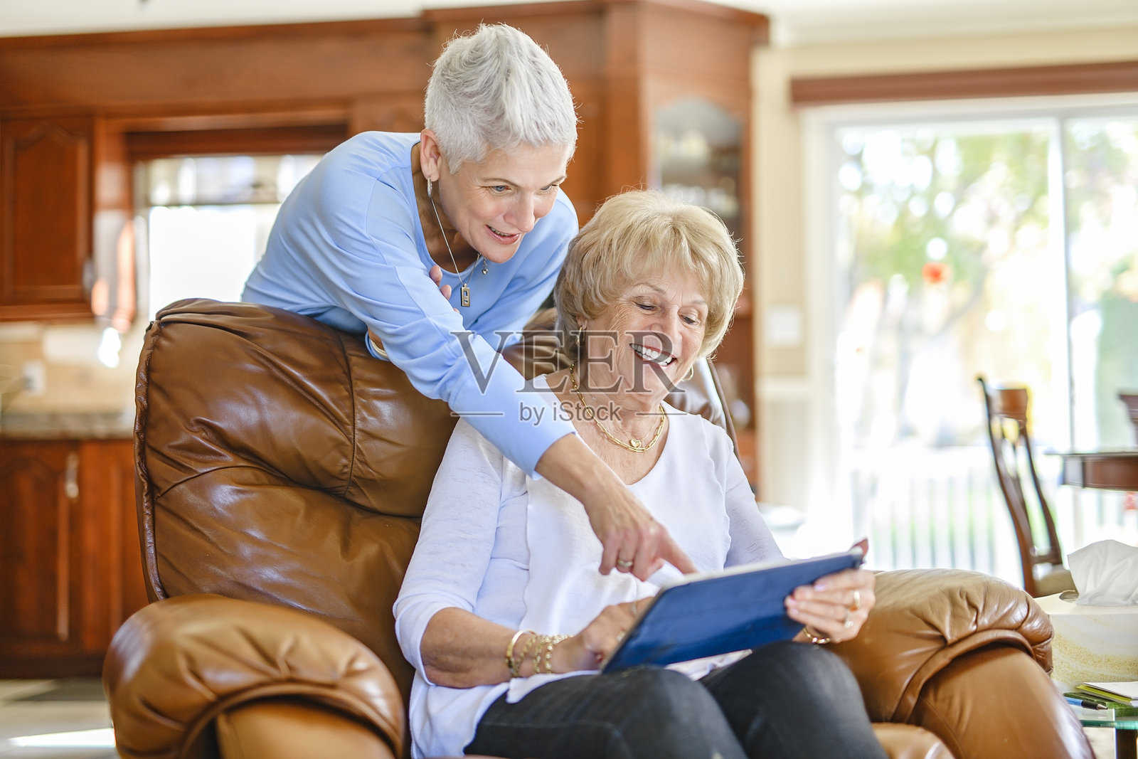 女儿在平板电脑上向年长的父母解释某事照片摄影图片