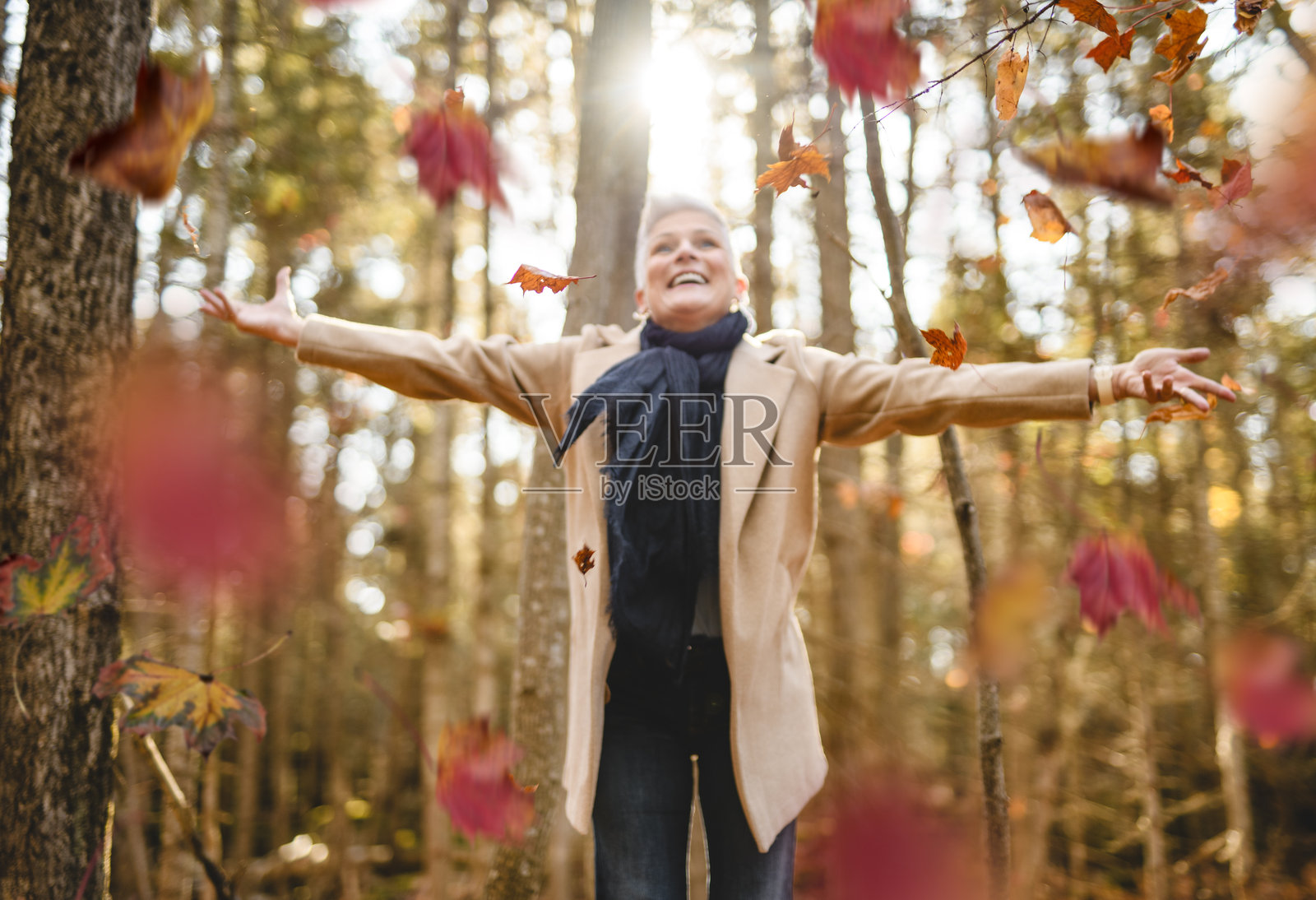 成熟的女性在秋季森林中，穿着舒适的秋季服装，与自然的反思与连接，身心健康照片摄影图片