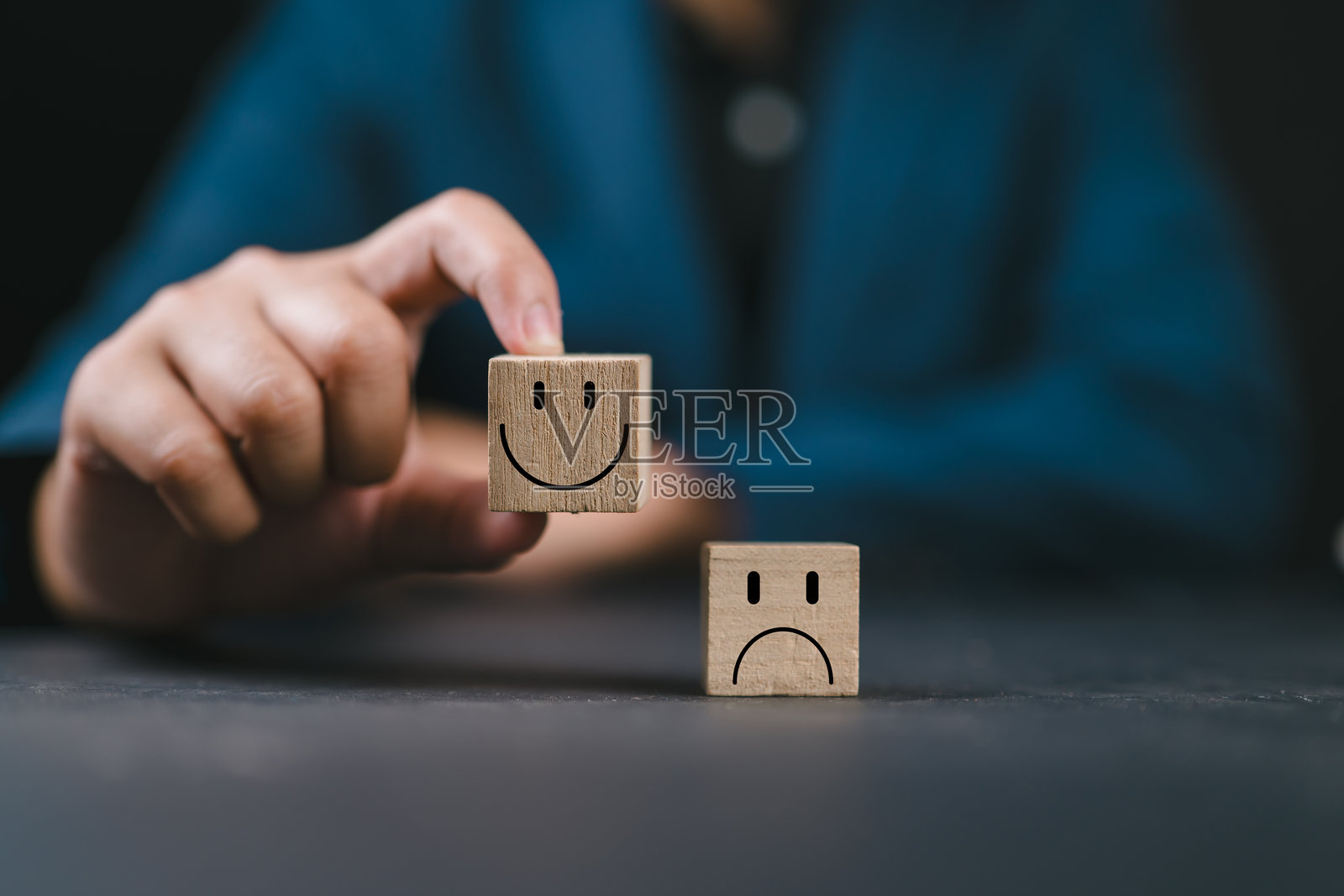 手握微笑的快乐脸庞木块，地面上是忧伤的情绪。世界心理健康日，反馈评分，客户服务评价。积极思考和满意度调查概念。照片摄影图片