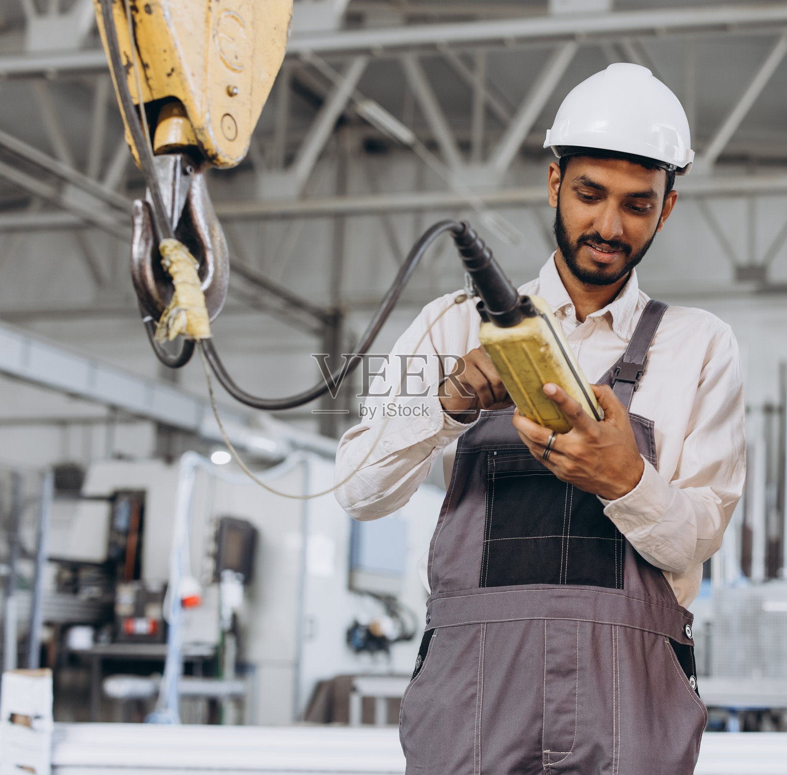 一名穿着特殊制服和头盔的印度工人手动控制电梯。照片摄影图片