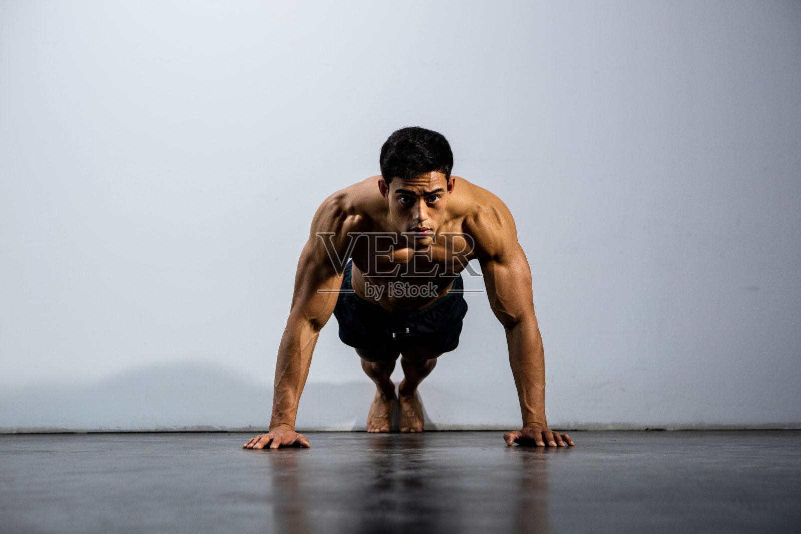 赤膊男对着墙做俯卧撑的肖像照片摄影图片