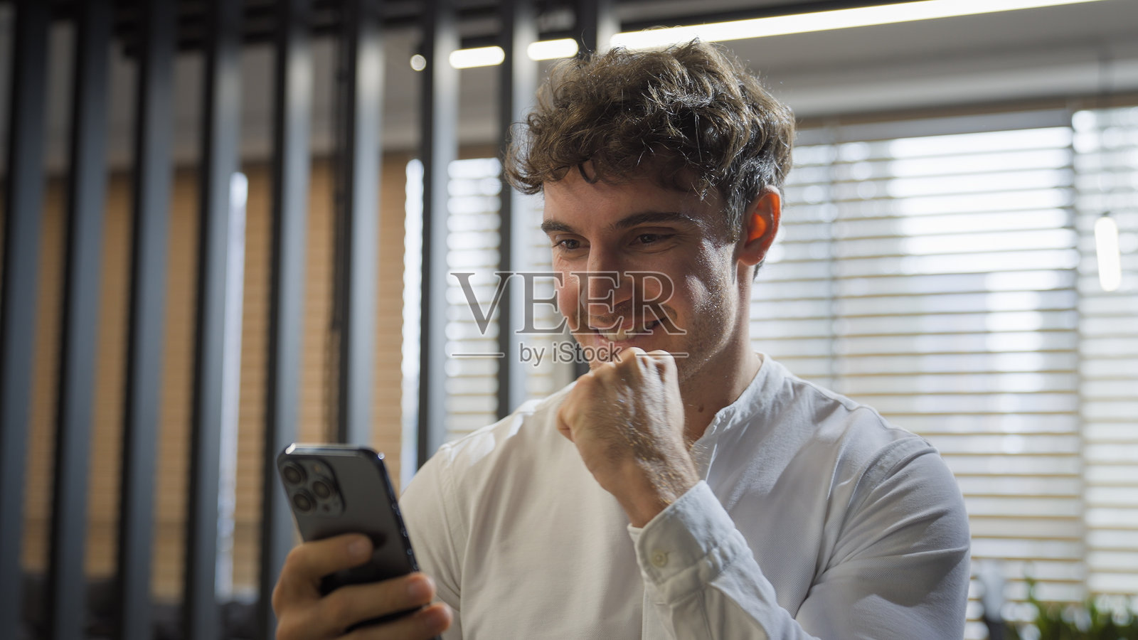 快乐成功兴奋的白人男商人在办公室内走动，阅读手机上的好消息，庆祝胜利。照片摄影图片