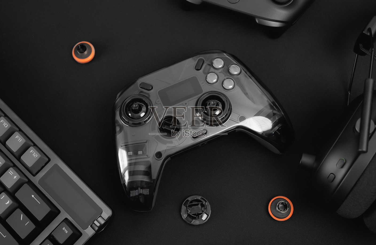 游戏工作空间概念，俯视黑色桌面上的游戏设备，包括鼠标、键盘、操纵杆、耳机、移动操纵杆、入耳式耳机和鼠标垫。照片摄影图片