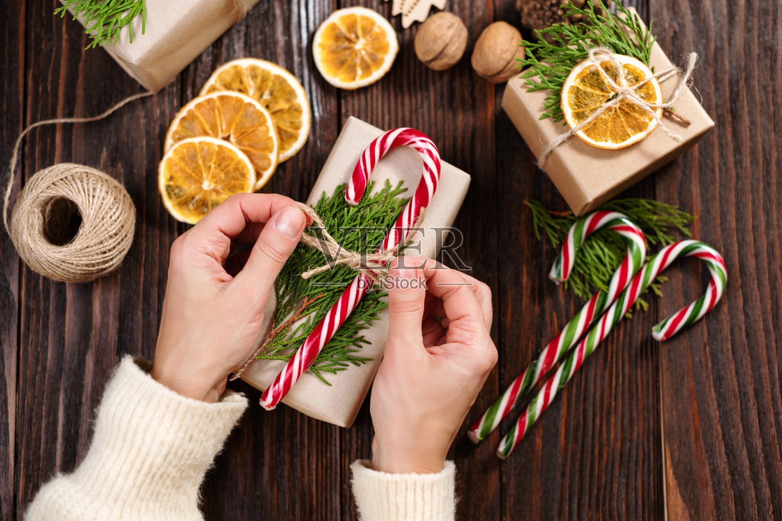 可持续的圣诞节。女性的手正在用手工纸包装圣诞礼物。环保圣诞假日概念。零浪费，环保。照片摄影图片