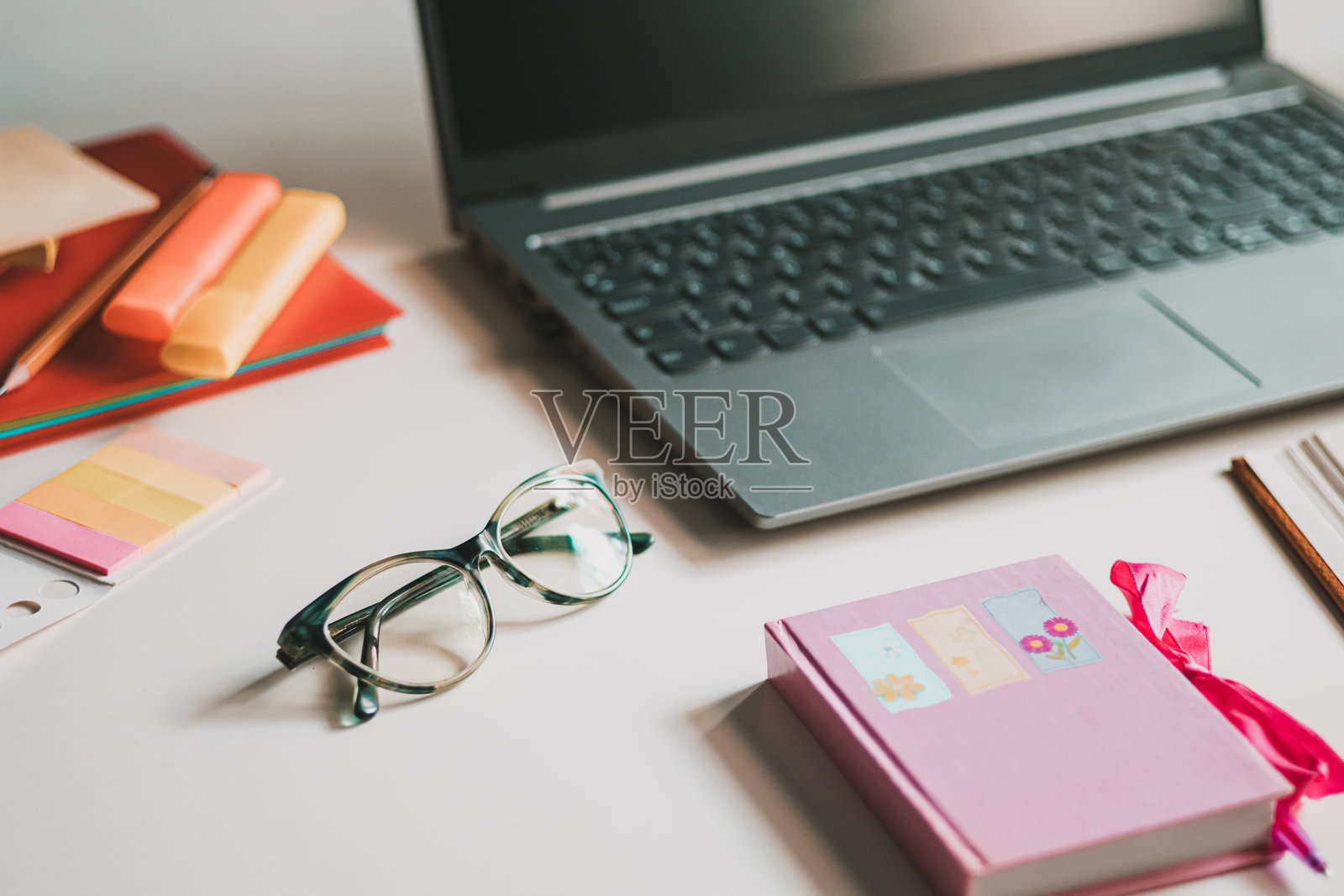 女性办公室桌子。笔记本电脑、咖啡杯、阅读眼镜和办公用品。照片摄影图片