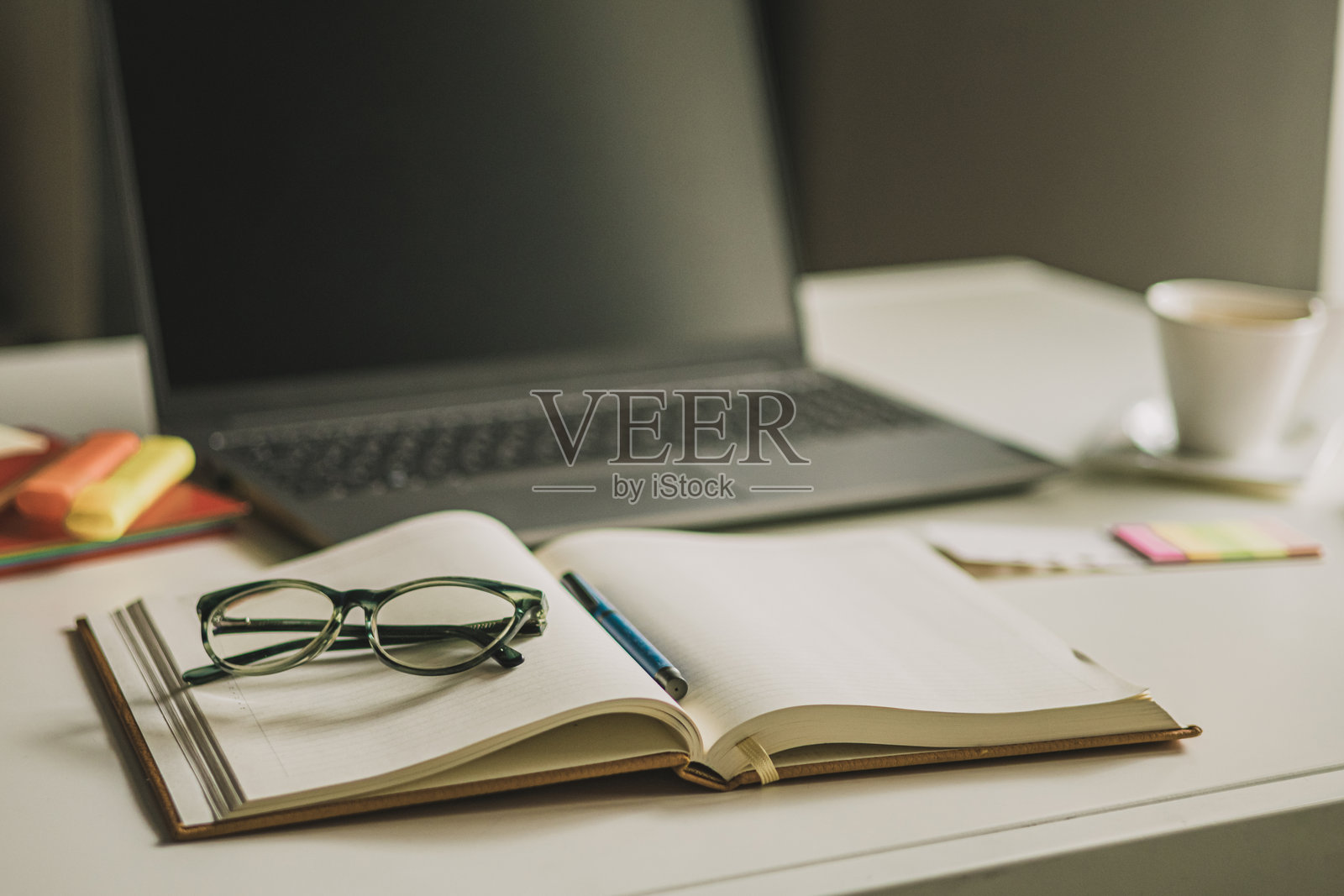 女性办公室桌子。笔记本电脑、咖啡杯、阅读眼镜和办公用品。照片摄影图片