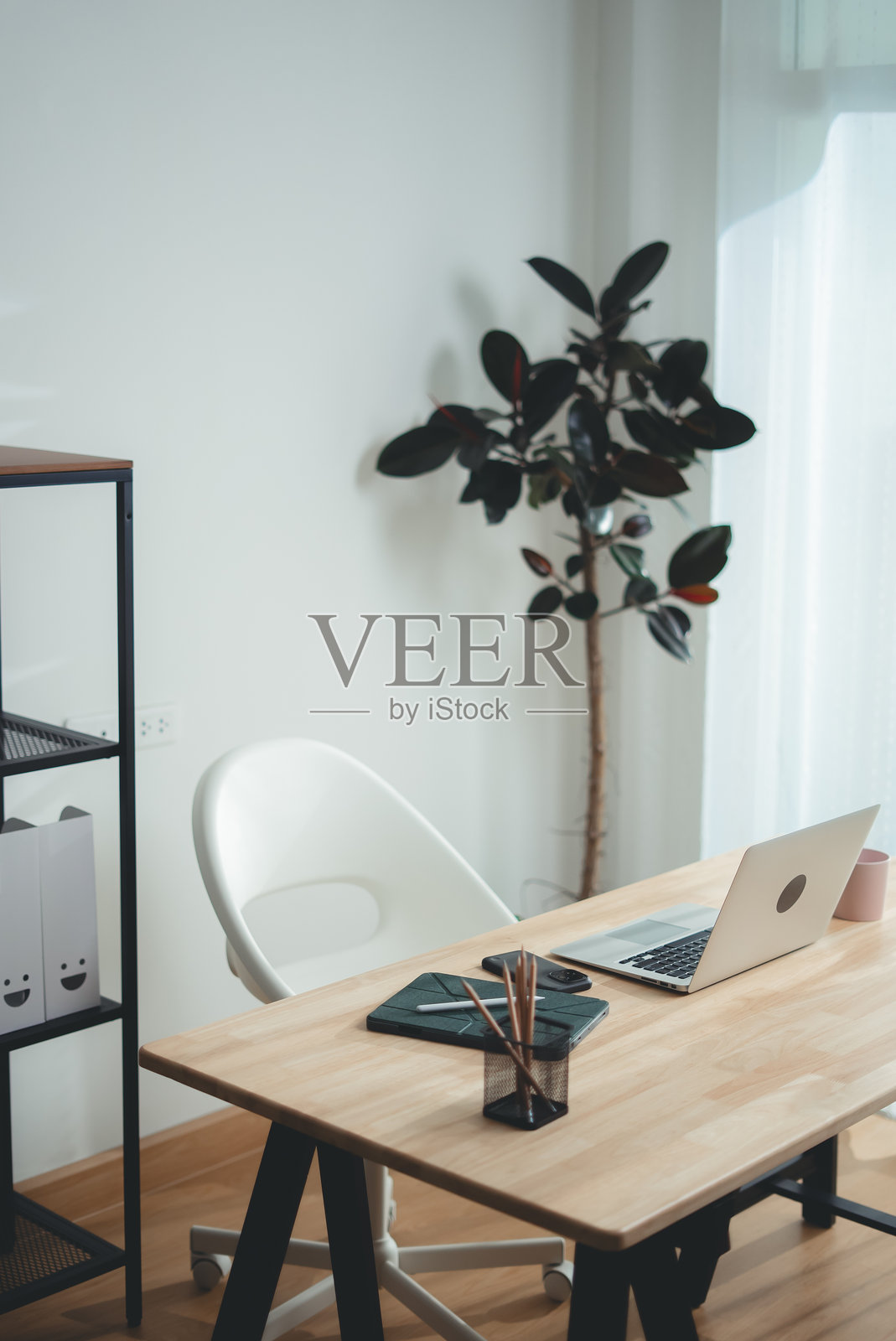 现代室内的木质书桌，上面有笔记本电脑和办公用品。照片摄影图片