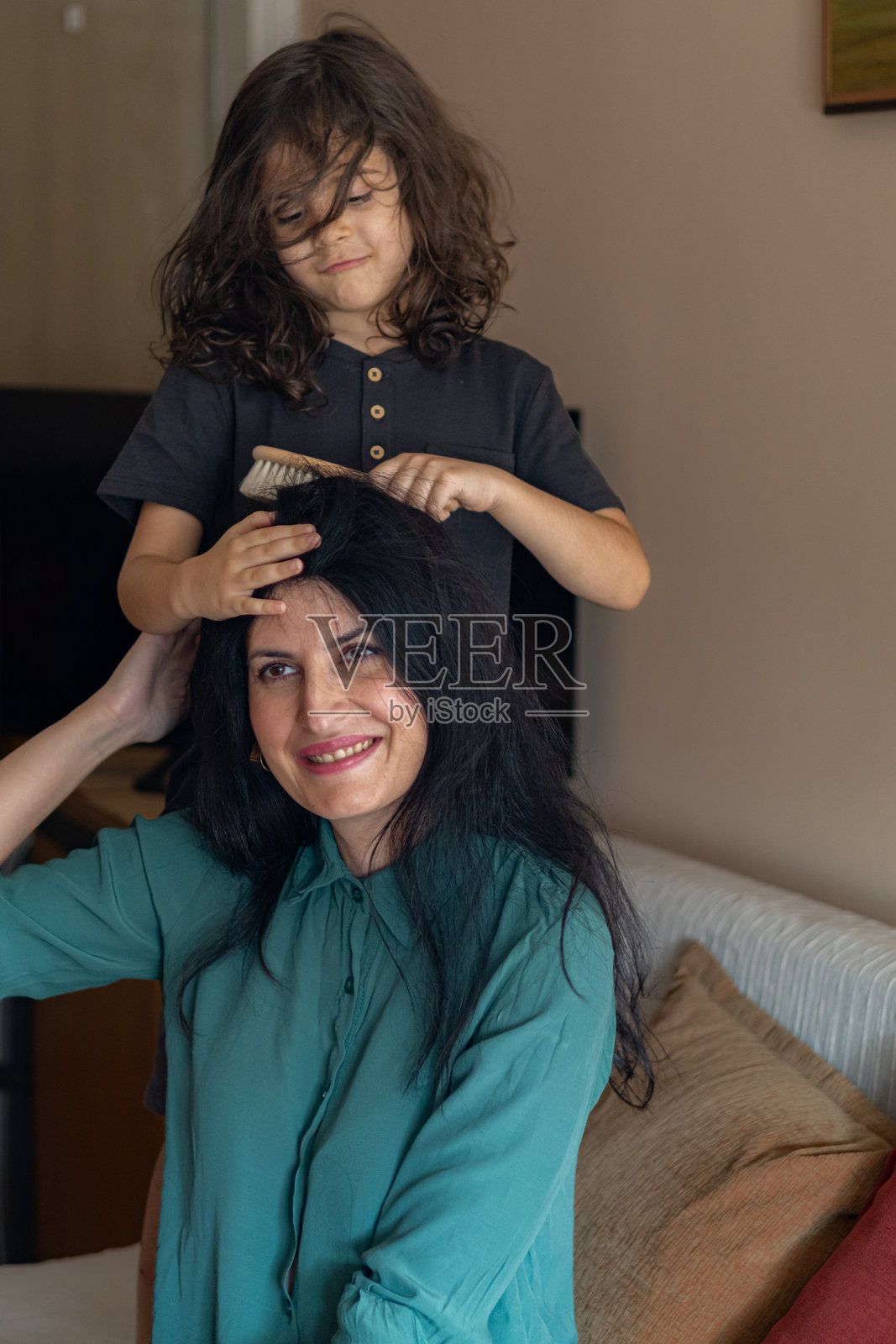 母亲和儿子在家客厅里梳理和吹干头发的亲密、快乐、顽皮时刻。照片摄影图片