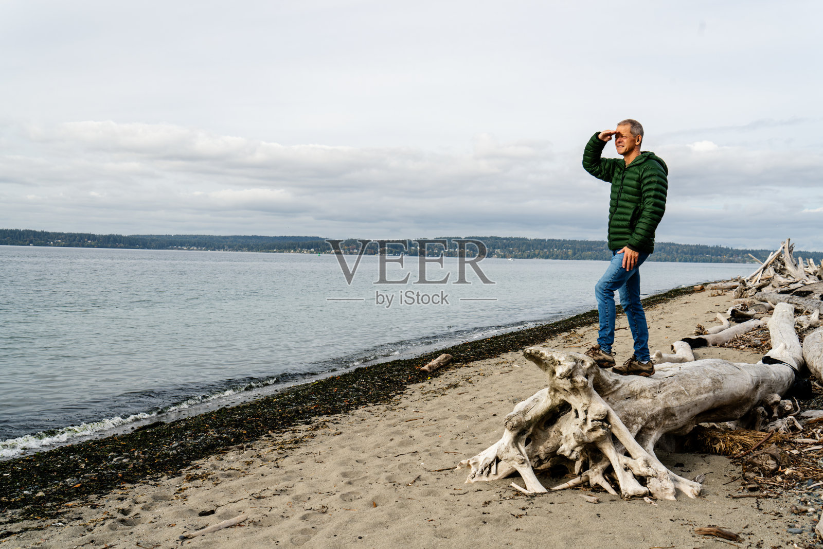 男人站在海滩上的漂流木上照片摄影图片