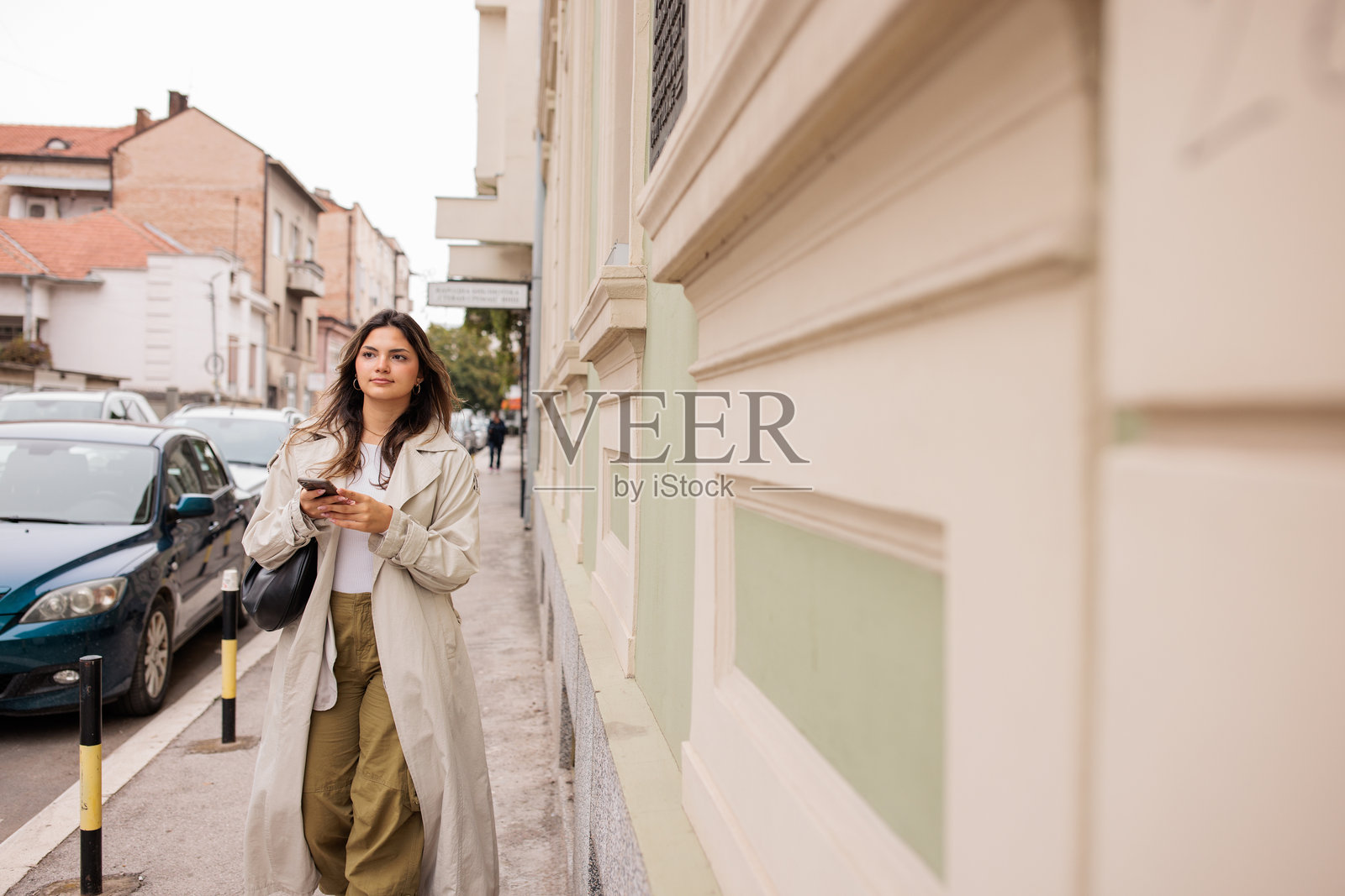 年轻女性在城市中走路时使用手机照片摄影图片