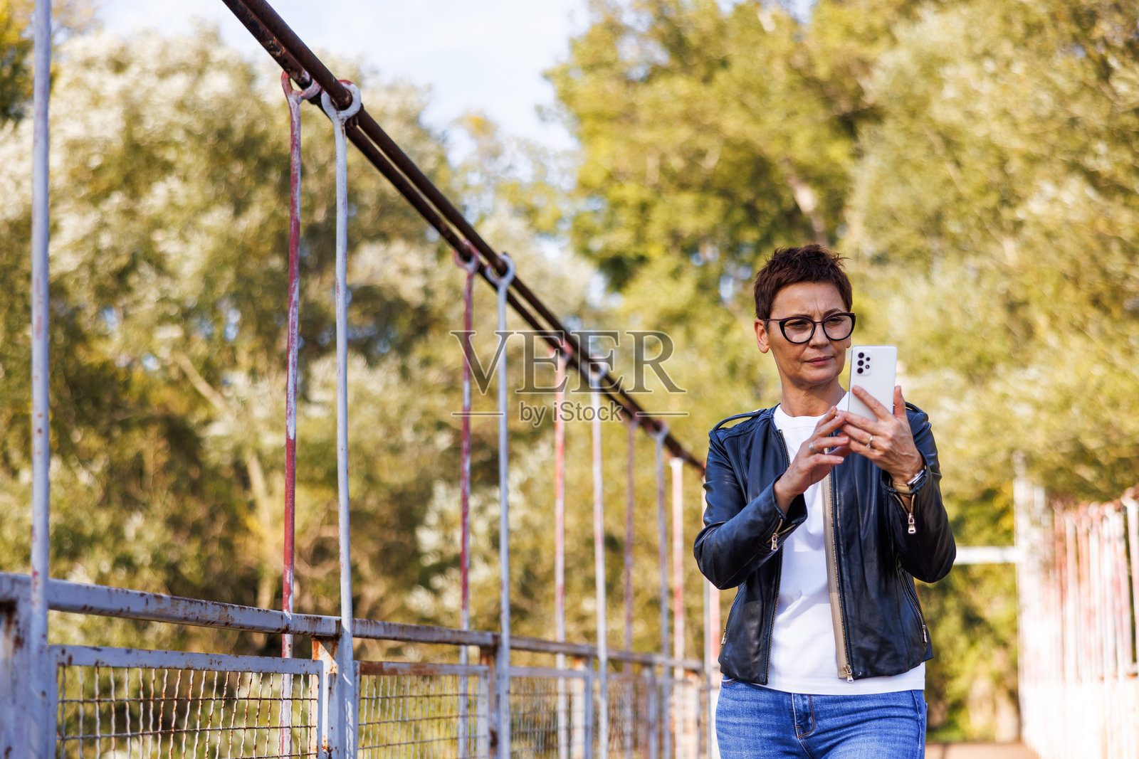 女士在户外走路时使用智能手机照片摄影图片