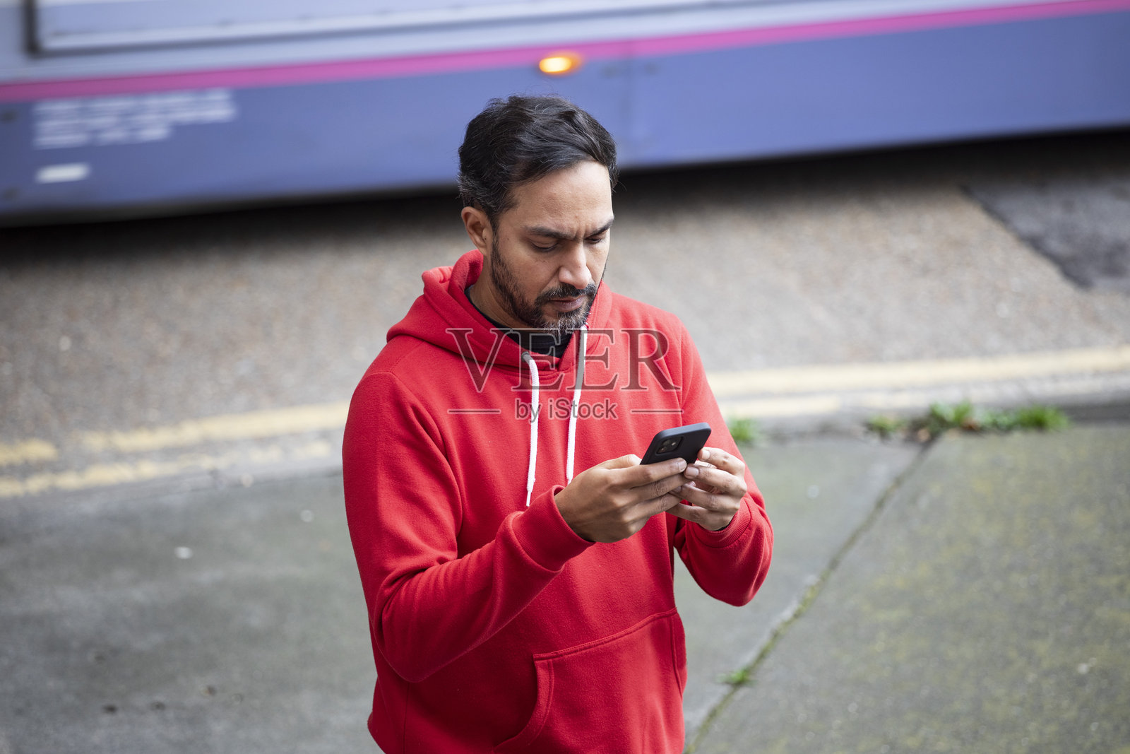 高处视角下，一名男子在交通繁忙的人行道上使用智能手机。照片摄影图片