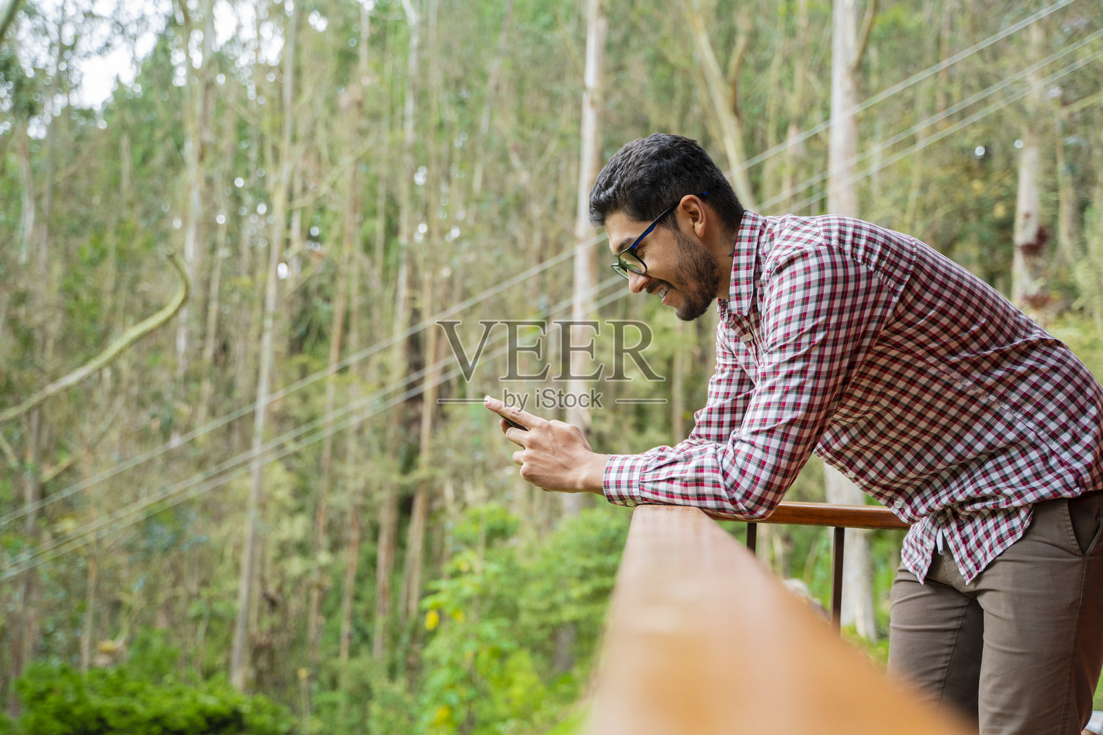 男子在房子的阳台上查看手机照片摄影图片