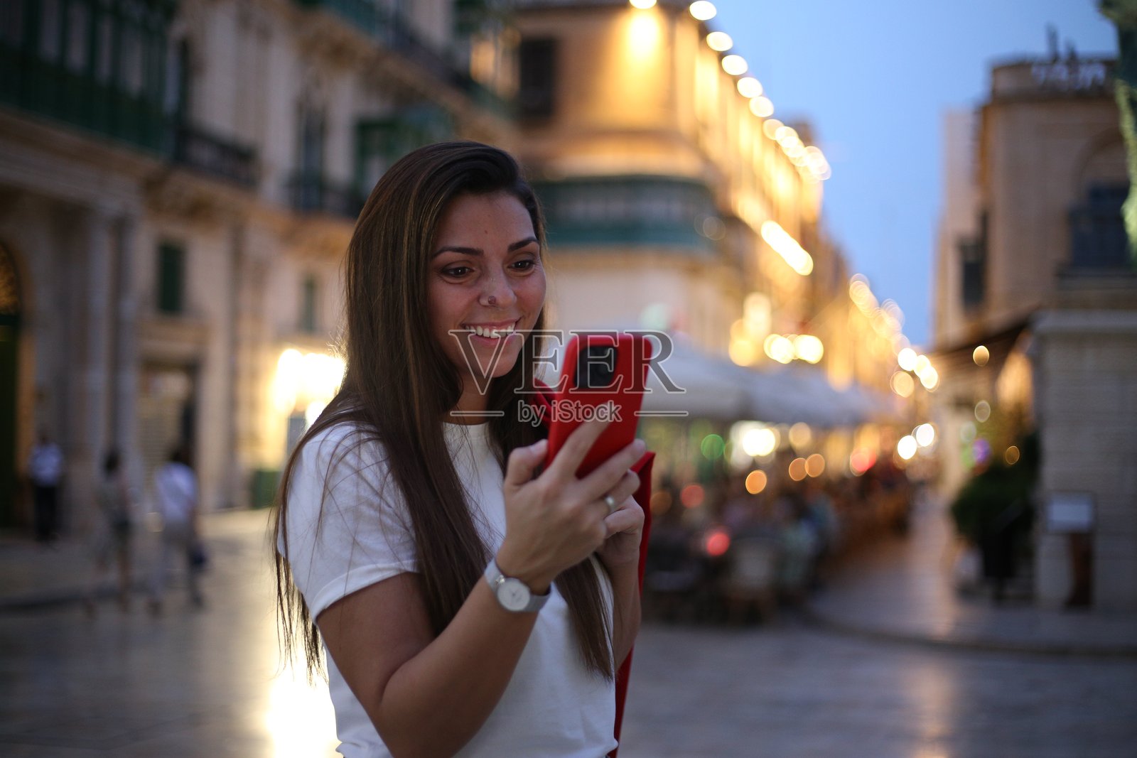 美丽的女性在城市街道上使用手机。照片摄影图片