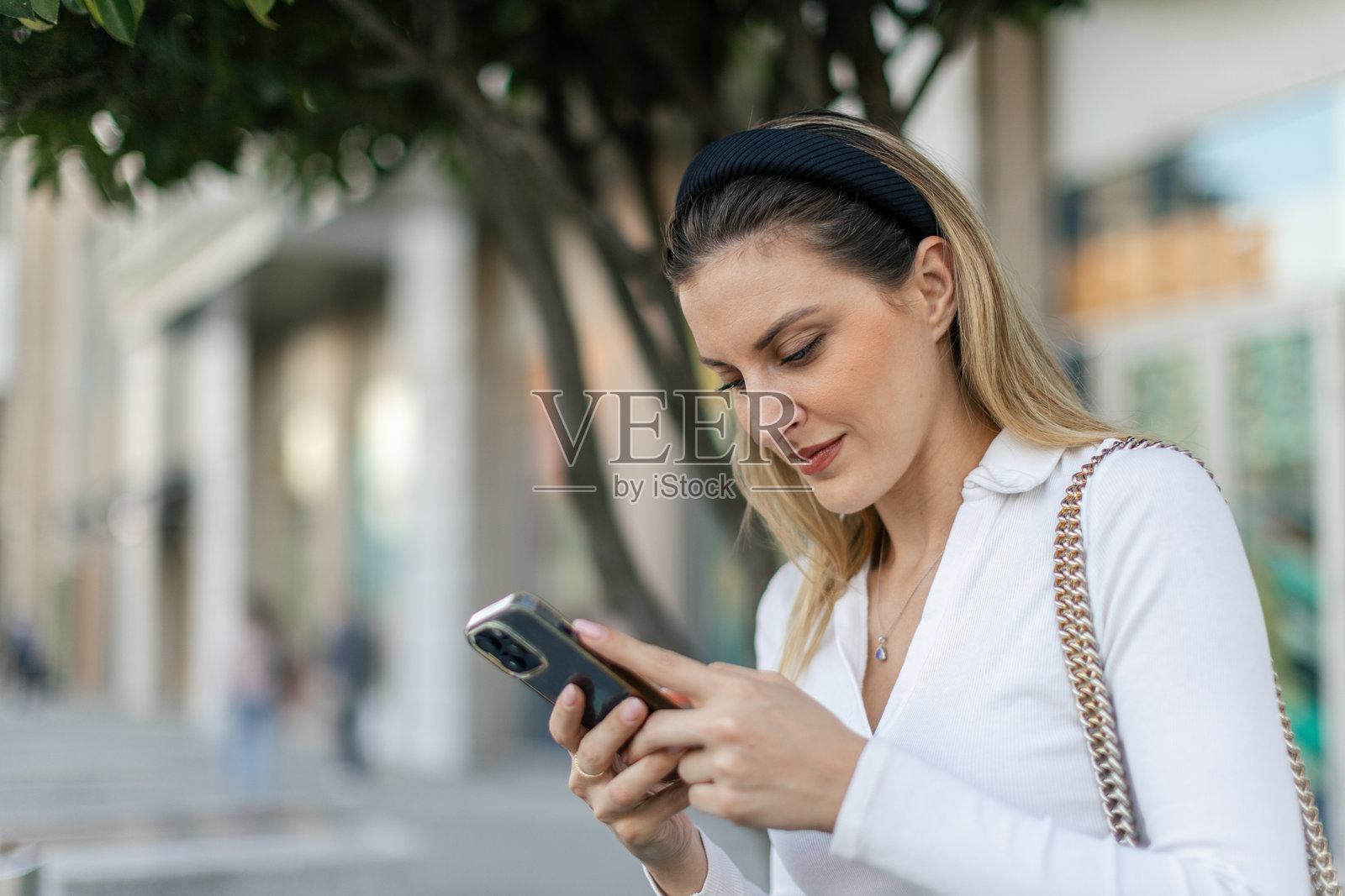 女人坐在街边长椅上，正在用手机打字照片摄影图片