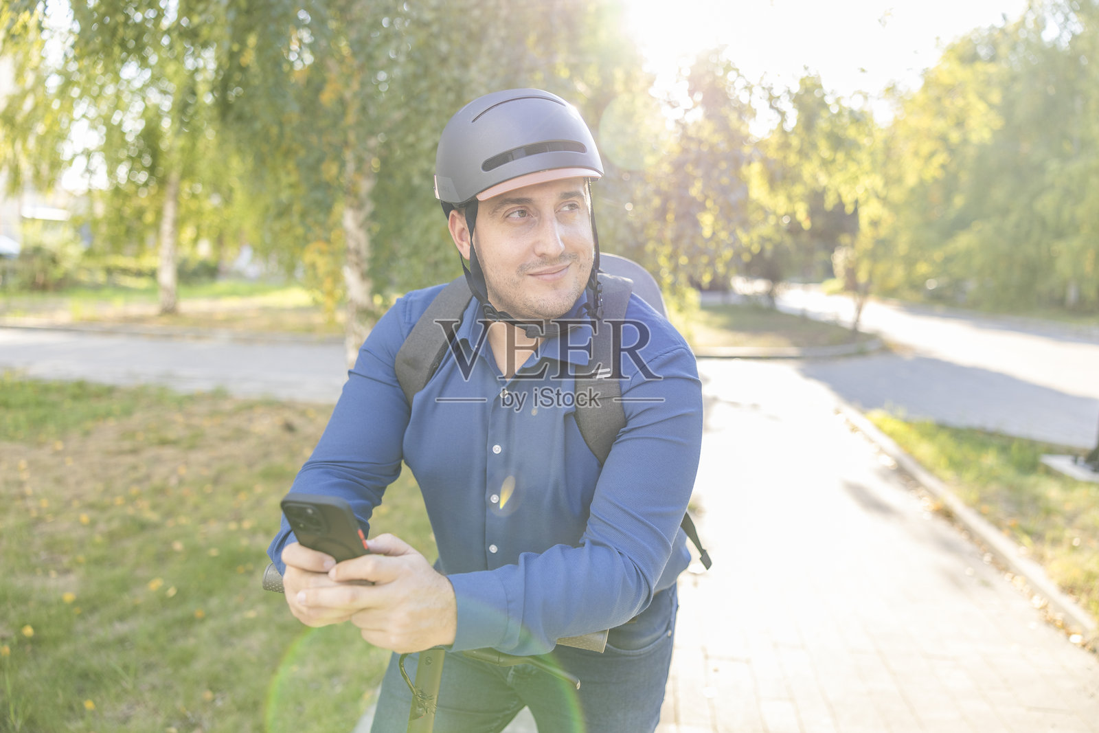 商务人士骑着电动滑板车，边走边使用手机。照片摄影图片