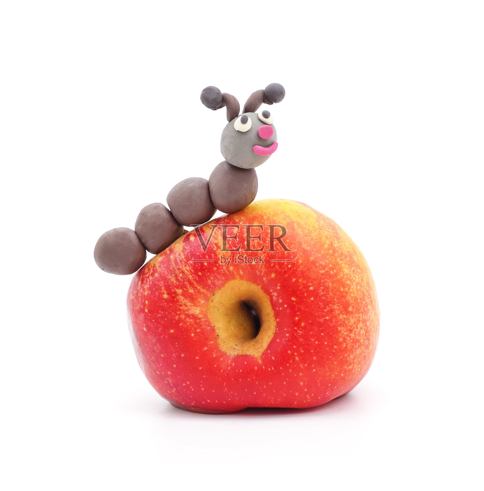 塑料泥毛毛虫旁边有一个带洞的苹果。照片摄影图片