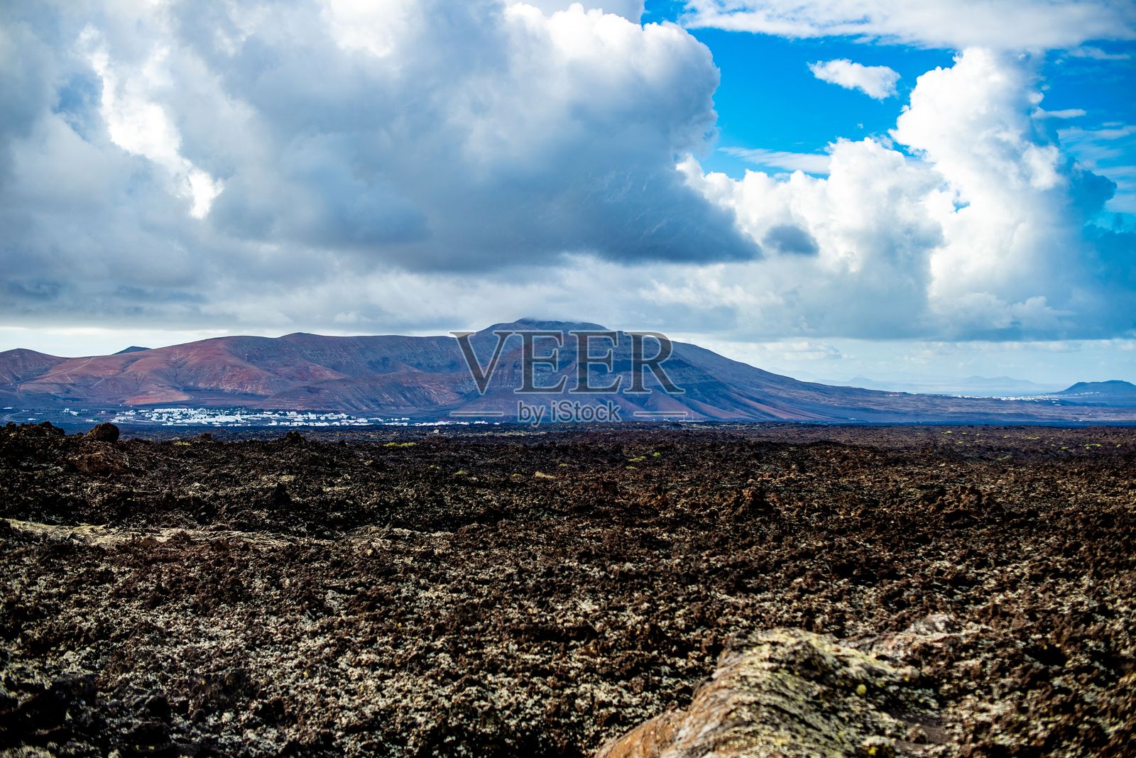 兰萨罗特岛上戏剧性云层下的火山景观。照片摄影图片
